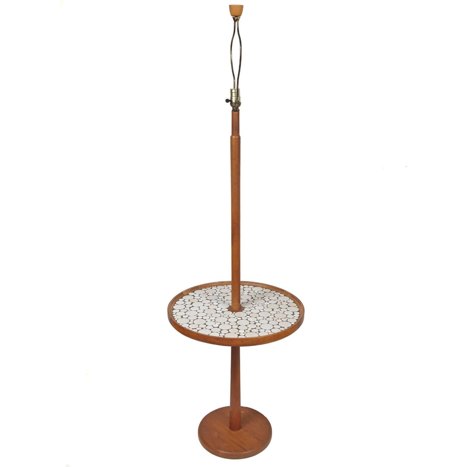 Walnut floor lamp by Gordon and Jane Martz. This beautiful lamp has a circular
table with round grey and white tiles. Appears to be original shade with wood finial. Made by Marshall Studios.