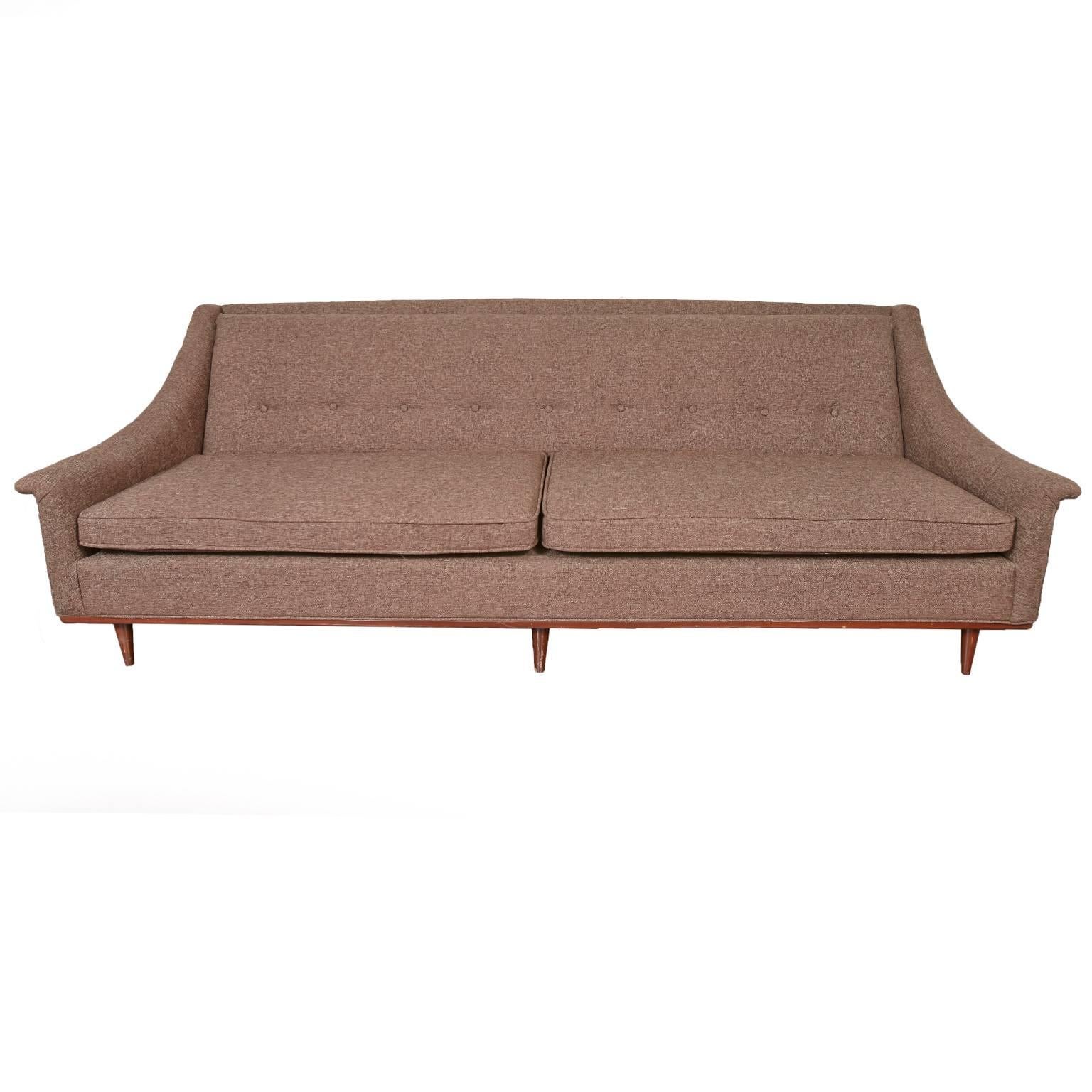 Newly upholstered Selig brown Mid-Century Modern sofa with five pillows,
two orange, and three brown.