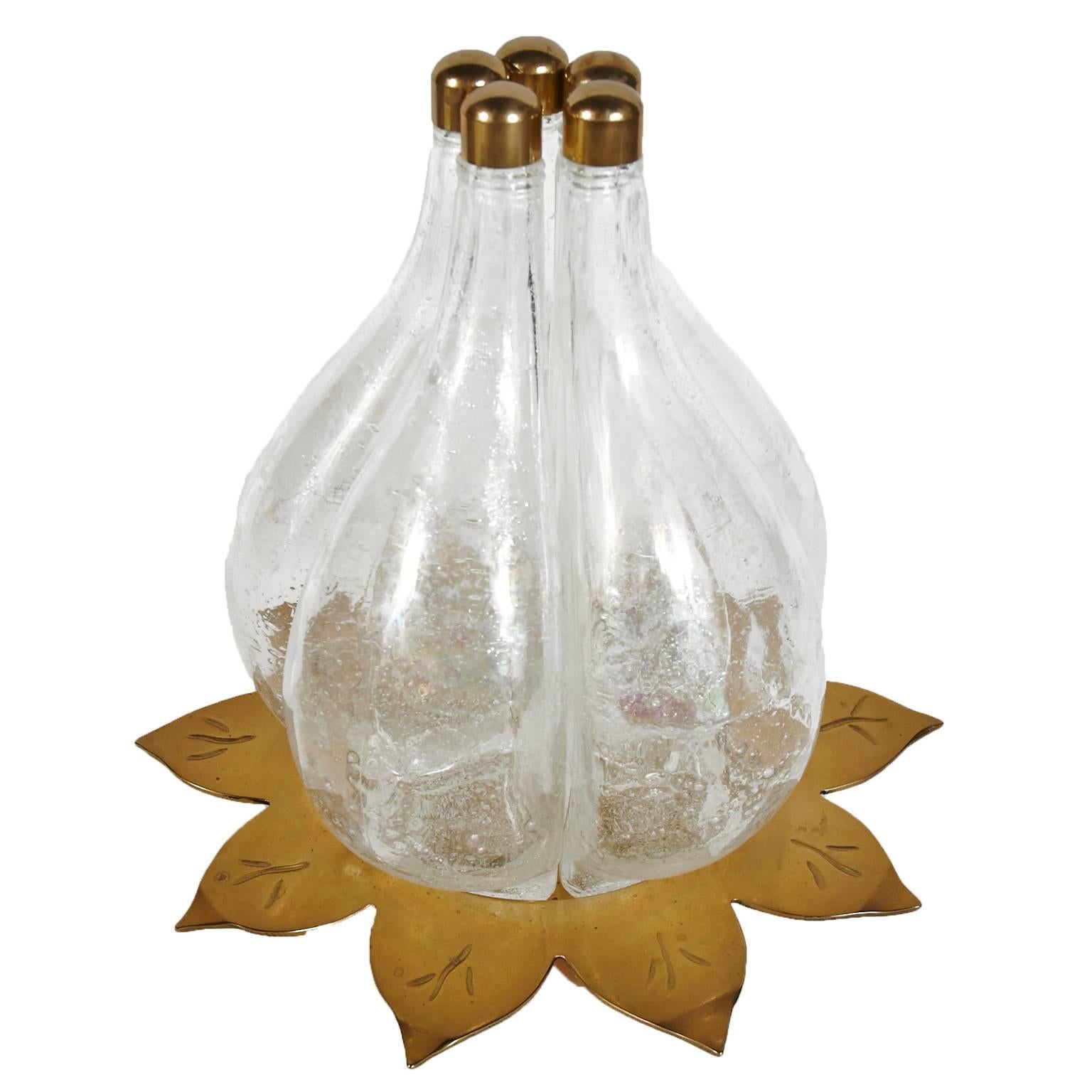 Unique brass and glass wine or beverage decanter. Five separate blown glass containers with brass tops set on top of a brass sunflower shaped holder. These separate pieces fit together and are held in place by the brass sunflower shaped base and the