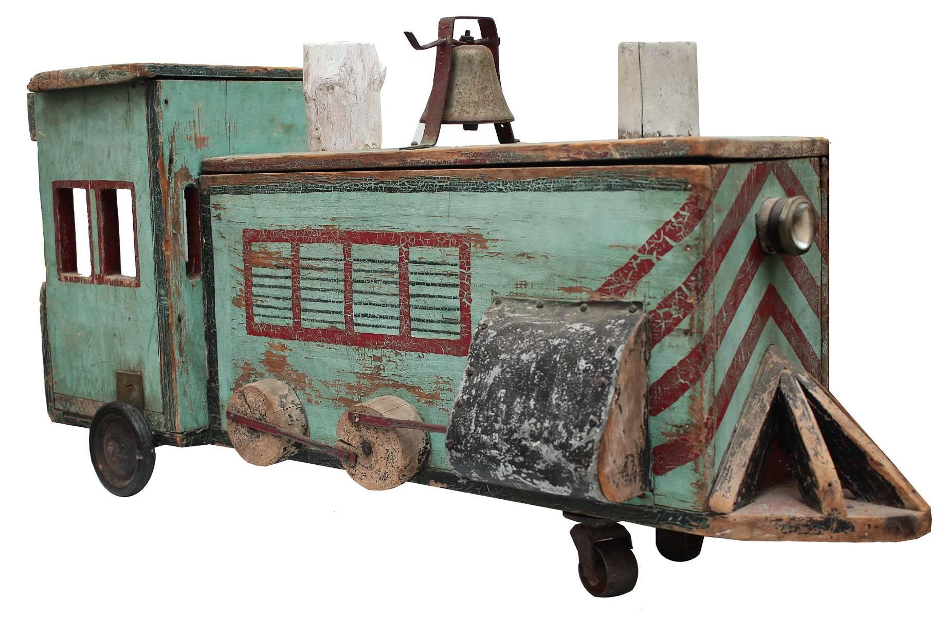 An amazing piece of American Folk Art. This train has all original paint, working wheels and a working bell. The top of the engine has a piano hinge that opens to a storage box. An wonderful and unique piece. Made of wood and finished with metal and
