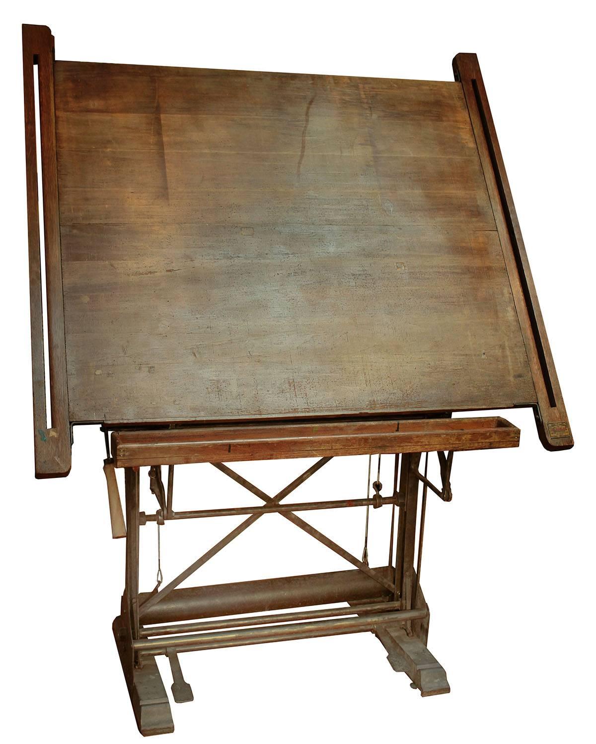 A beautiful piece of function and style. This drafting table dates to the early 20th century and works as well today as the day it was made. Solid cast steel base houses a counter weight that allows the top to move up and with ease. A heavy truly