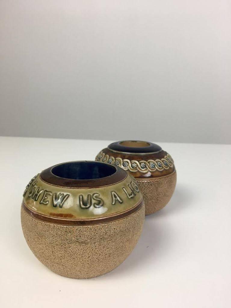 Pair of Victorian round stoneware match strikers from Royal Doulton. One with decorative pattern the other with the words “Shew Us A Light” in raised text around the rim.

Both stamped on the base.

Dimensions: 3