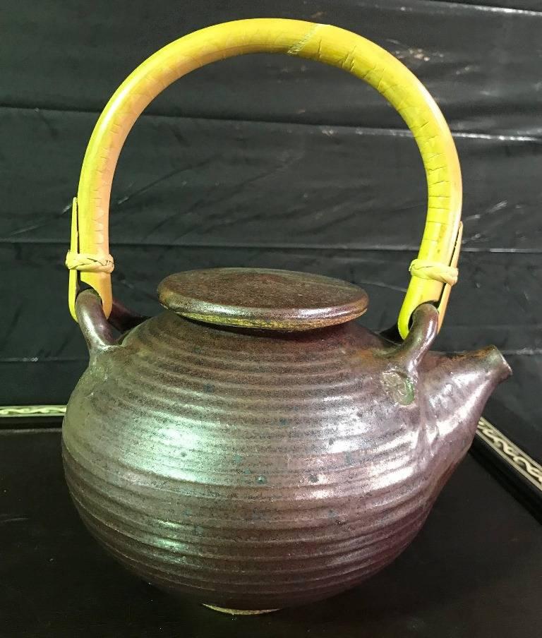 A beautifully designed and glazed earthenware teapot by ceramics masters husband and wife artists Vivika and Otto Heino. The two were best known for their inspired designs and distinctive glazes. This darkly colored teapot is signed on the underside