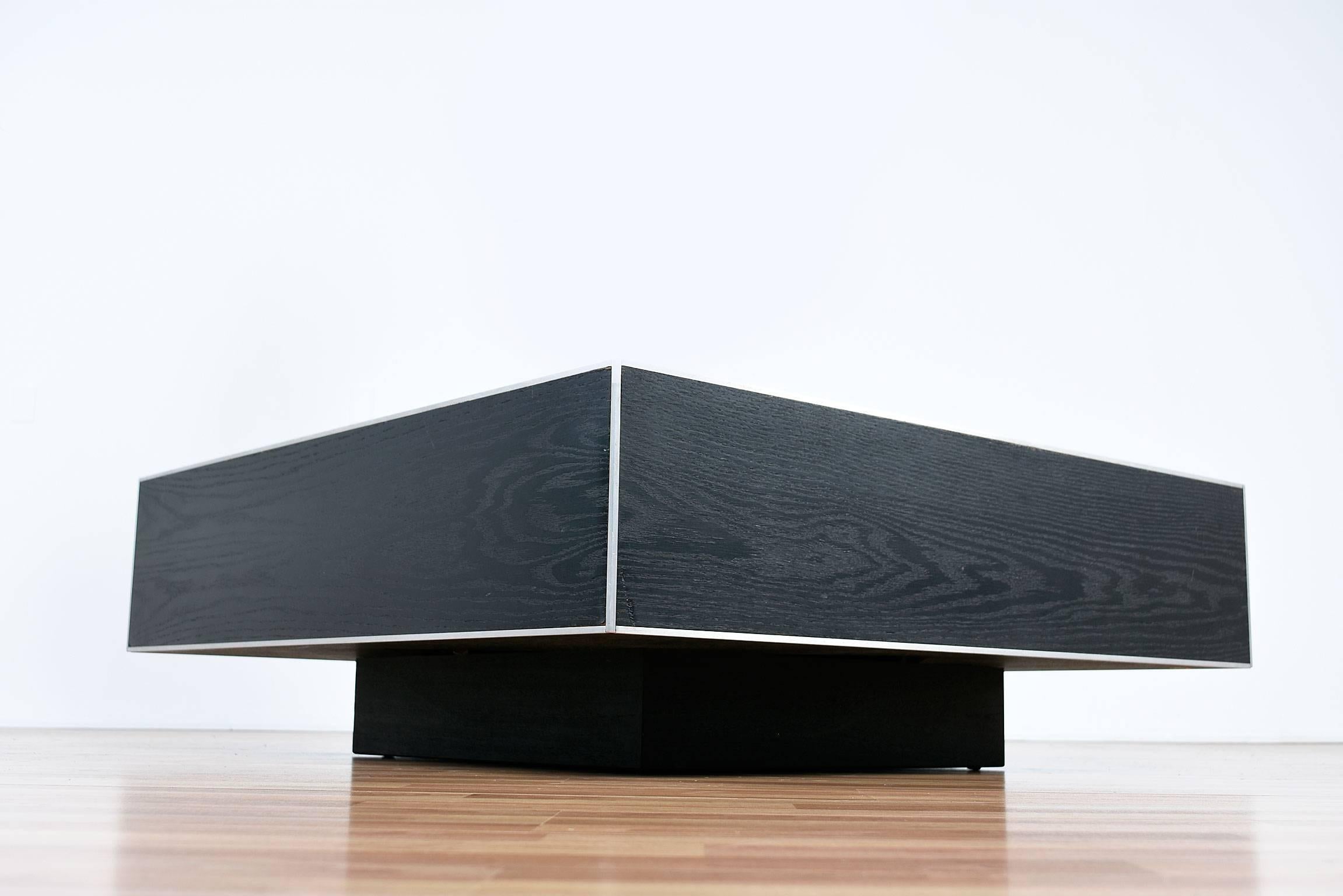 Unique monumental modern English coffee table featuring historical crests of the 13 notable English families. Textural and intricately embossed raised laminate perched on a low pedestal cube base.