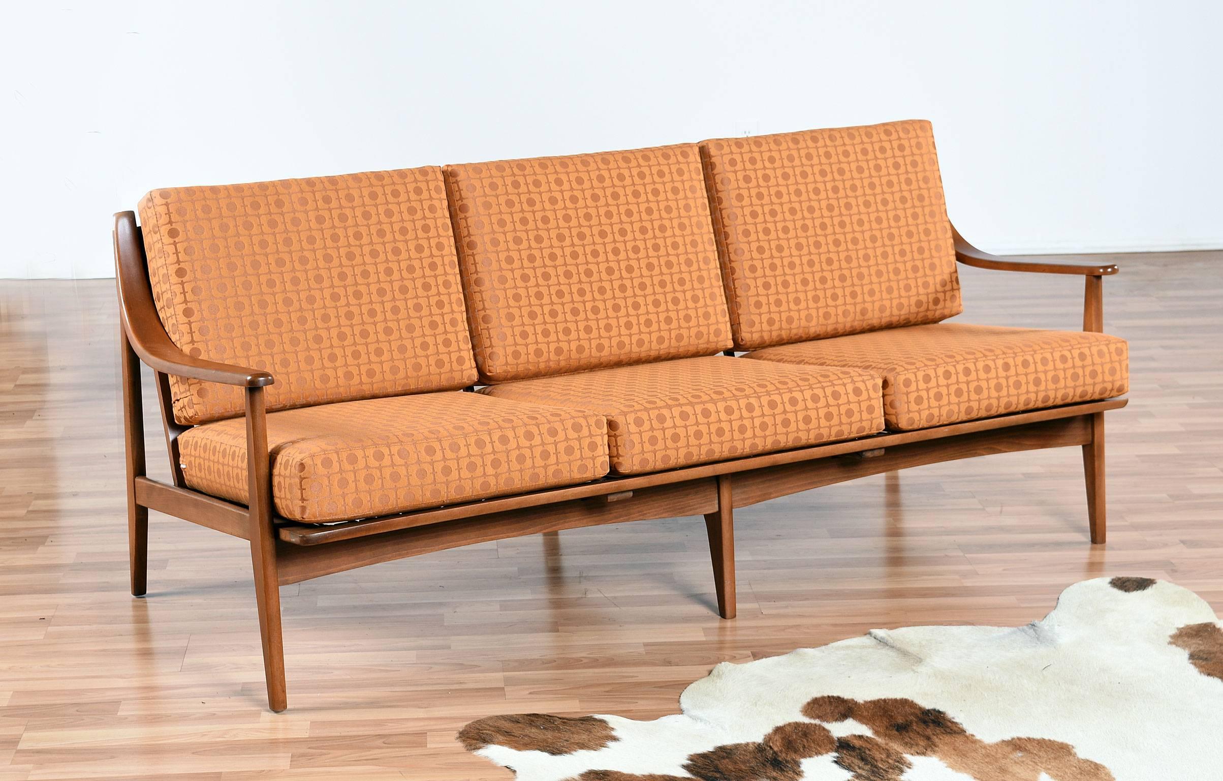 Lots of period charm in this restored Mid-Century Modern sofa. The gracefully sloped arms mimic Scandinavian designs adding an air of elegance to this American made couch. The sofa has been updated with new webbing straps, new cushion foam and a