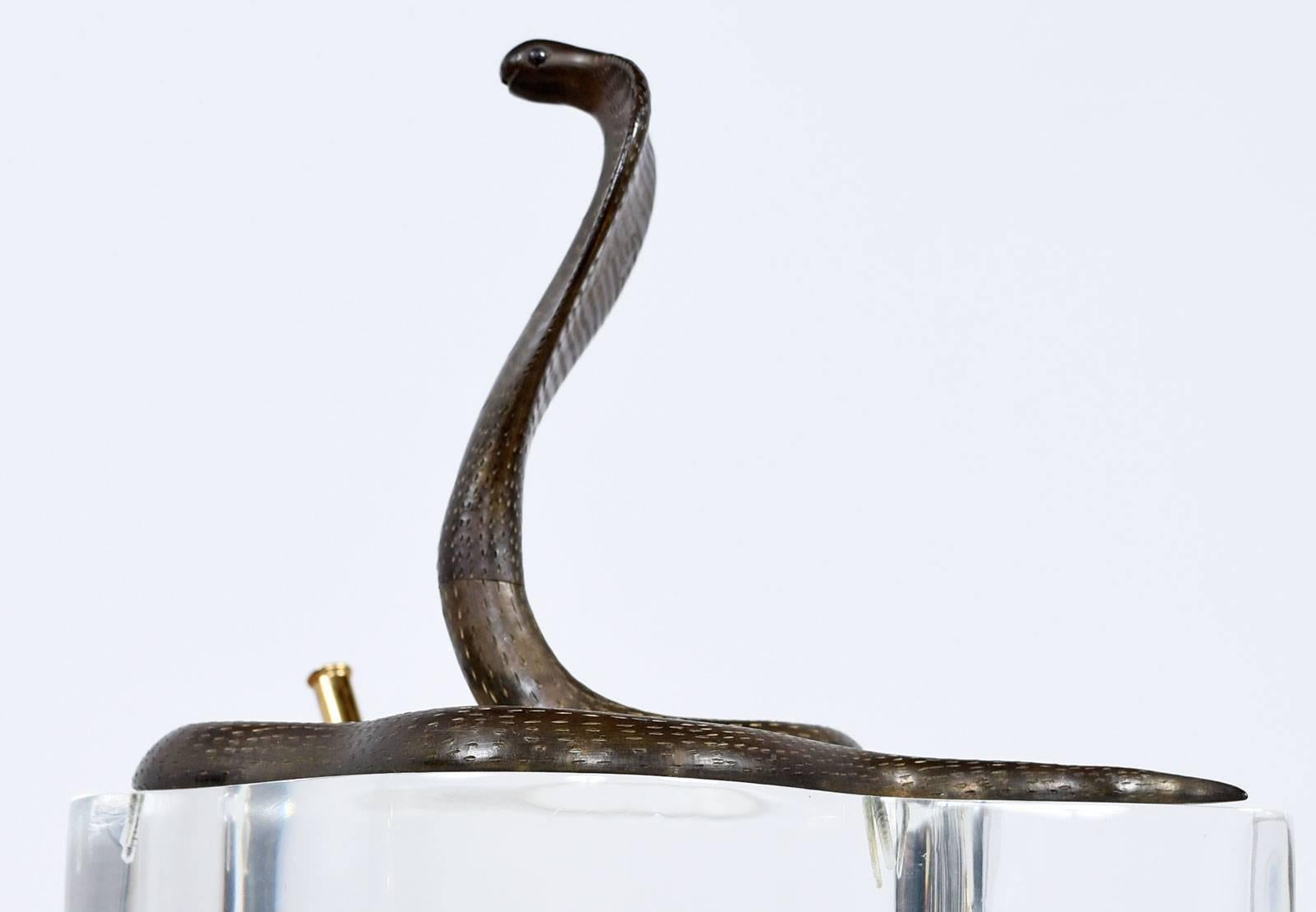 Vintage Lucite and brass double pen holder from the 1970s. This unique sculptural piece features a large brass king cobra sitting atop a thick V-shaped Lucite base with a brass pen holder on each end. It's signed by the artist on the back.