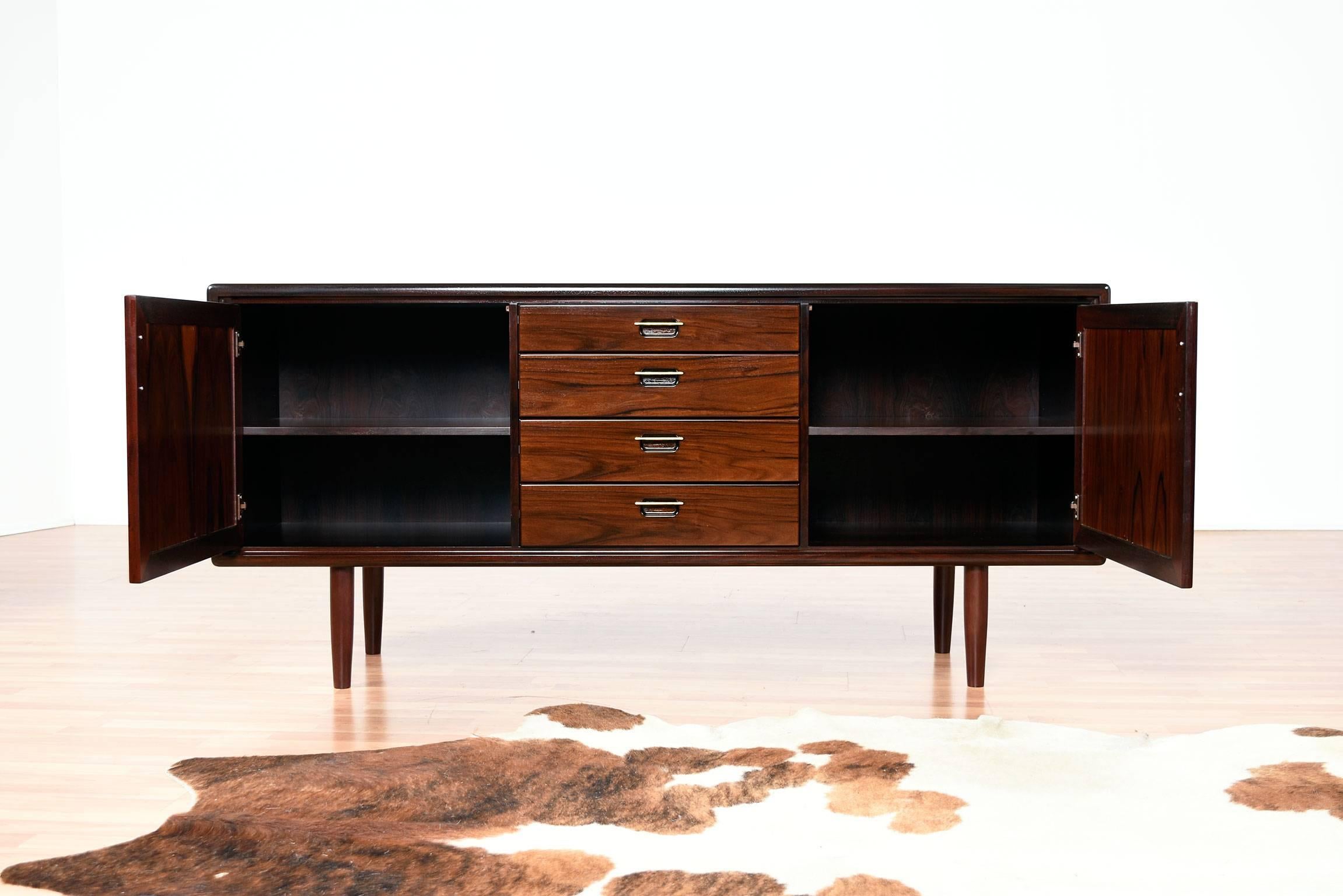 Stunning vintage rosewood credenza made in Scandinavia. This piece is a sight to behold in person. The wood is a rich black cherry color with elegant contrasts of lights and dark in the grain. The clean lines of the Danish Modern work to enhance the