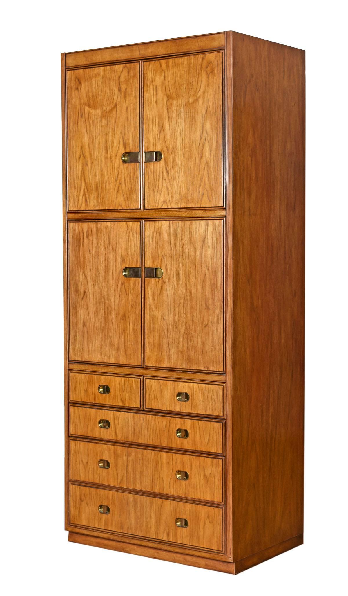 Pair of Mid-Century Modern illuminated cabinets by Drexel Heritage from the Preface Collection. The set is decorated with original brass hardware, made of pecan wood, and dates to the 1970s.These tall shelving towers are slightly different in their