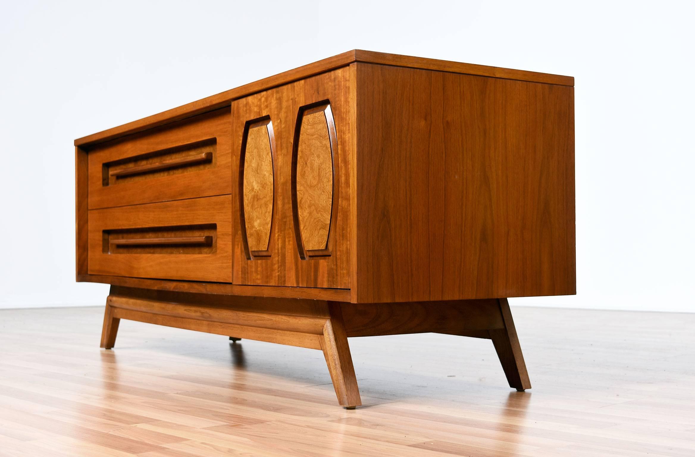 This beautifully detailed low profile Mid-Century Modern dresser is made by Young Furniture in the 1960s. This exquisite dresser is made of walnut with burl accents around the solid walnut sculpted drawer pulls and sculpted relief embellishment on