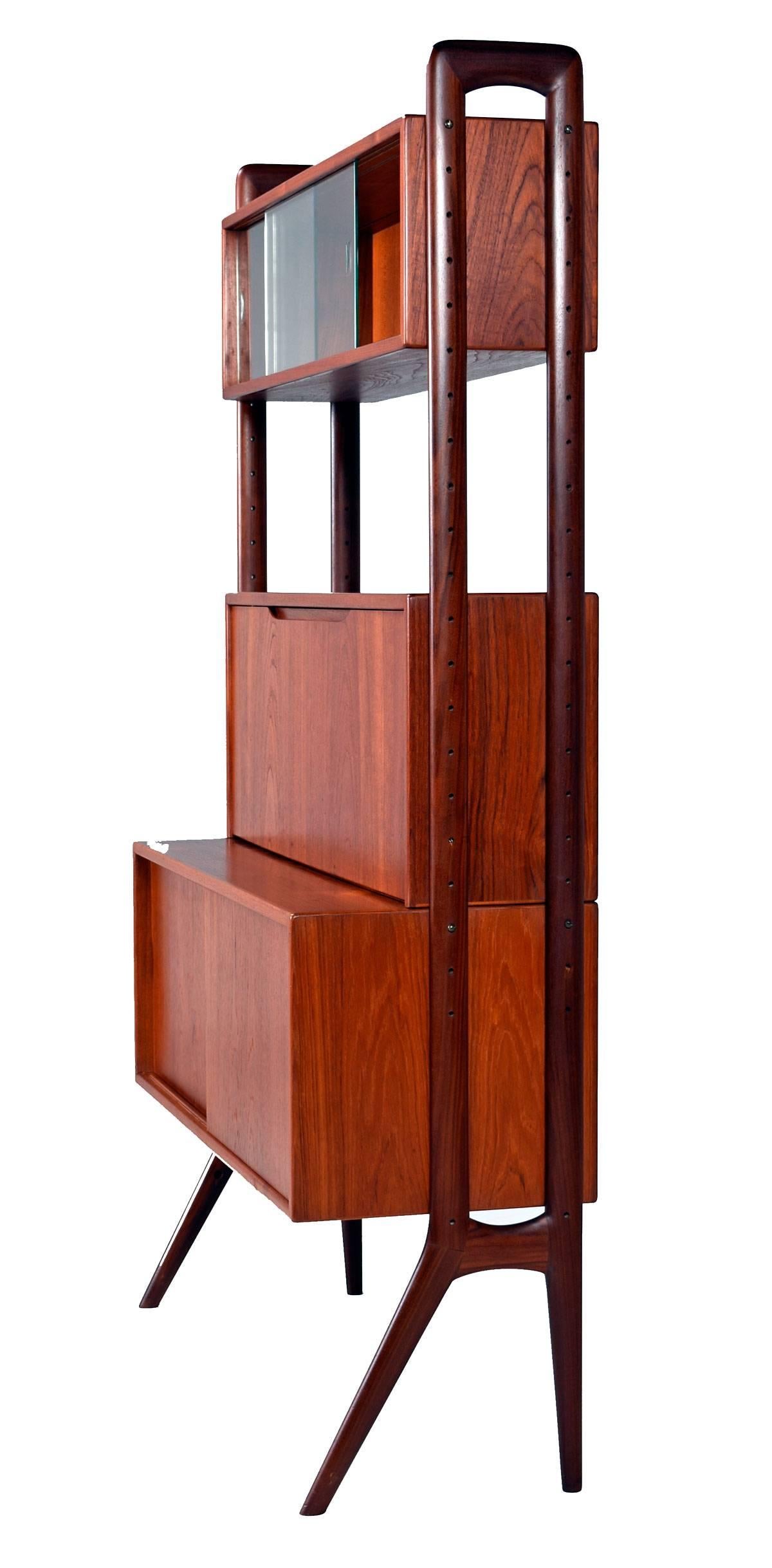 Gorgeous Scandinavian Modern open modular teak wall unit room divider by Kurt Ostervig. Features three adjustable cabinets, one sliding double door large cabinet with a movable shelf, a smaller glass front sliding door cabinet and a medium sized