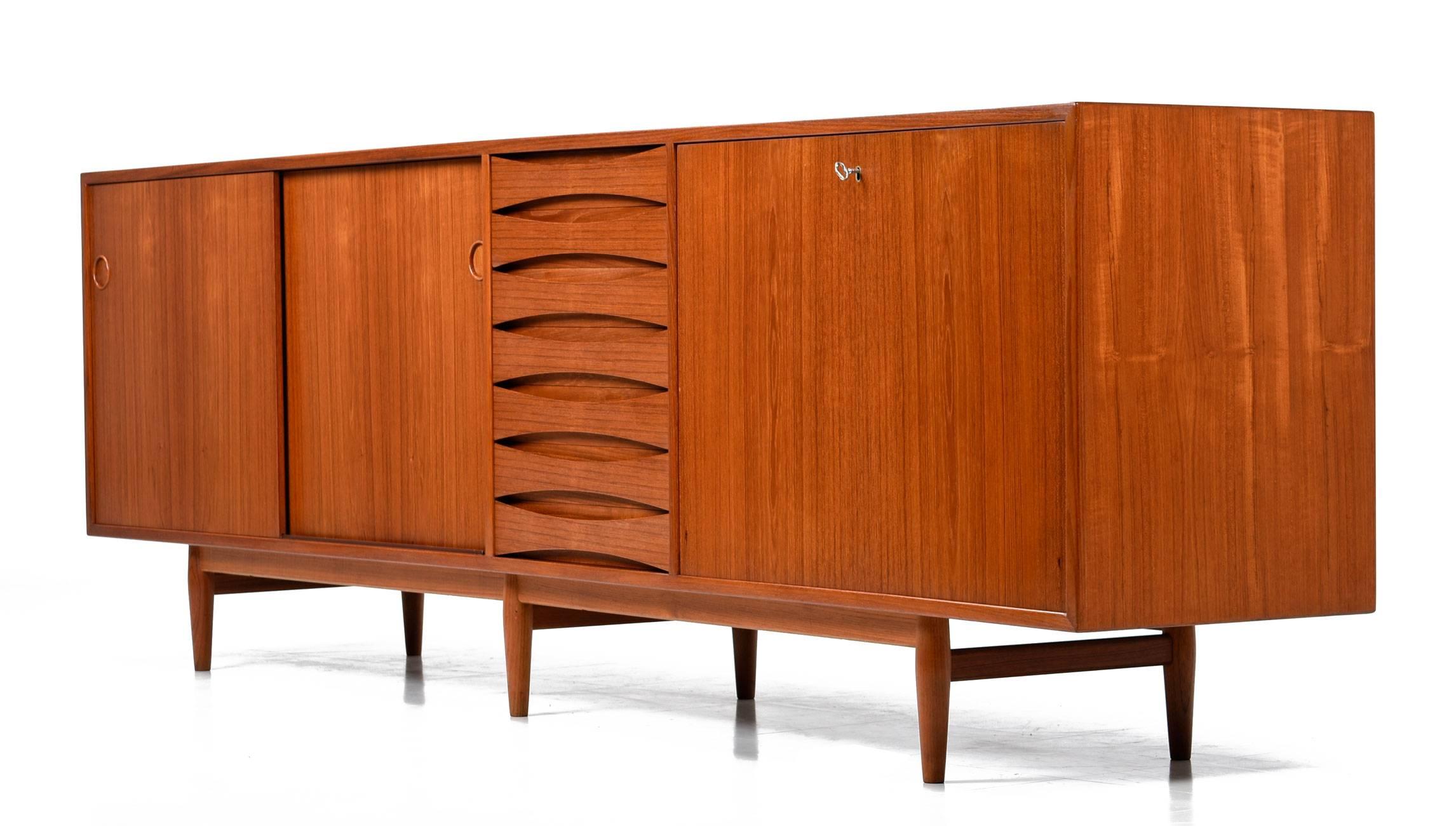 Gorgeous Arne Vodder teak credenza model 29A for Sibast Mobler, circa 1950s. This iconic and impressive, 8' long sideboard features exquisite craftsmanship, clean architectural lines, solid teak recessed concave drawer pulls, and a finished back. It