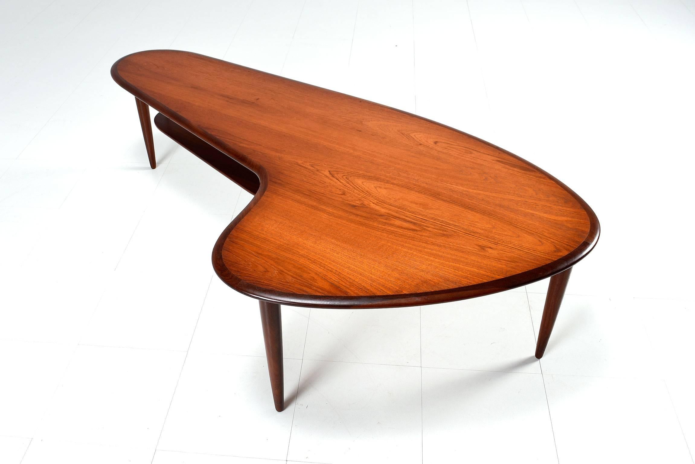 Gorgeously sculpted Danish teak boomerang coffee table, made in the late 1950s. Scandinavian Modern take on this Classic shape, dark rich patina of the aged teakwood, rounded solid teak edges, tapered straight legs and featuring a suspended magazine