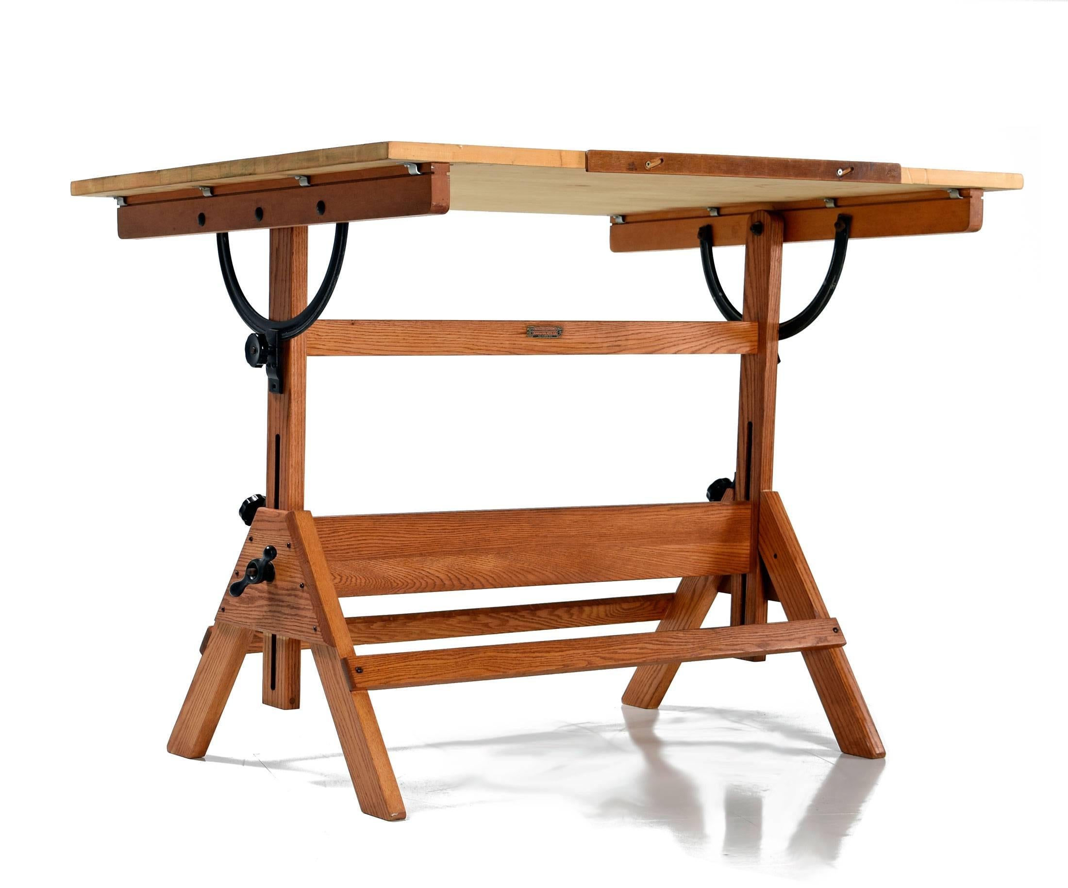 Original drafting table manufactured by Hamilton in the US in the 1940s. This large work table features an oak base, pine tabletop and cast iron hardware. This large tabletop articulates to be either completely horizontal or pitched at varying