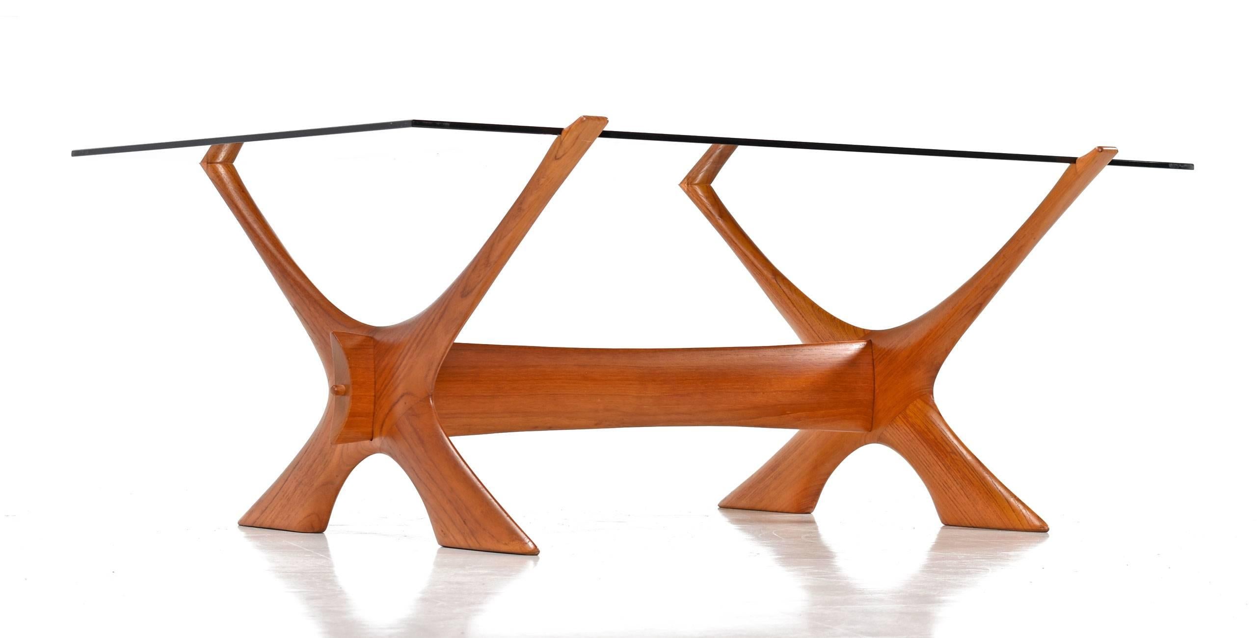 Beautiful and iconic condor coffee table designed by Fredrik Schriever-Abeln for Örebro Glass of Sweden in the 1960s. The timeless design features a carved solid teak X base, with notches at the ends which support and hold a thick smoked glass