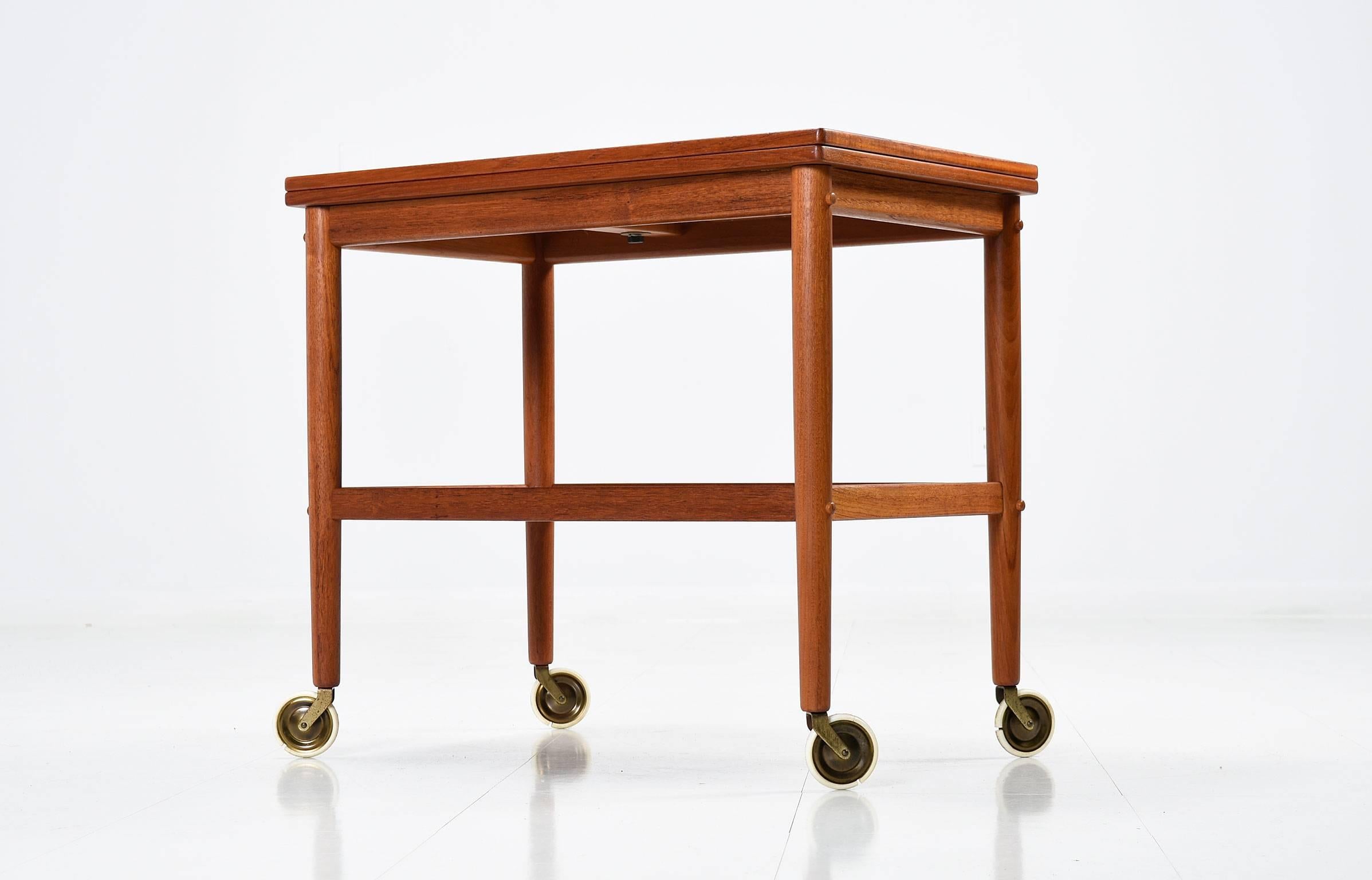 Mid-Century Modern Grete Jalk for Poul Jeppesen tea cart or serving bar cart, made in Denmark 1950s. This stunning tea cart has a unique design feature, the top slides to one side, turns 90 degrees and expands to twice the size. This piece bears the