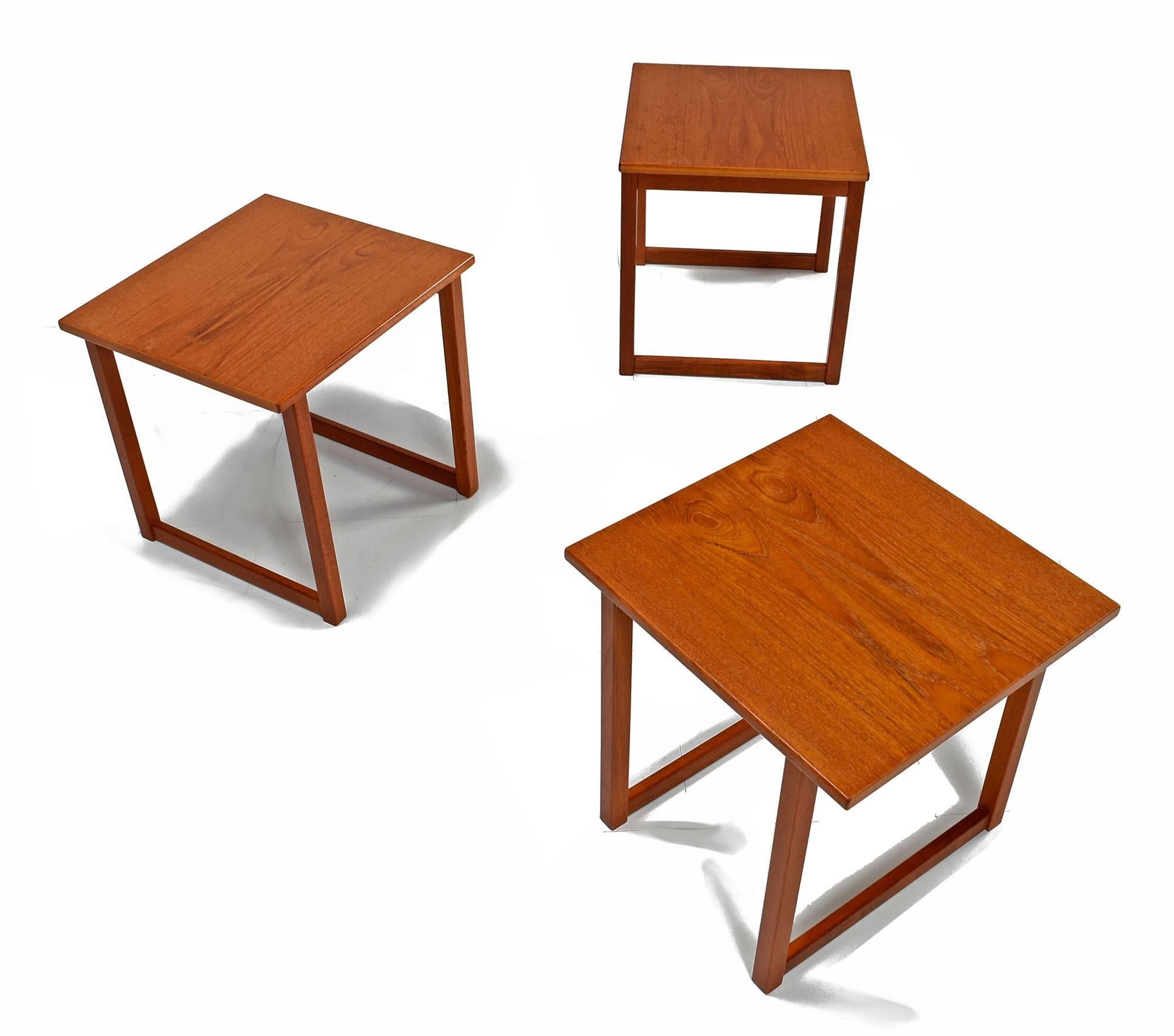 Scandinavian modern set of Kai Kristiansen "Cube" nesting tables. This handsome set contains three identical Danish teak tables which can be arranged in a variety of ways, making them multifunctional; they also stack together forming a