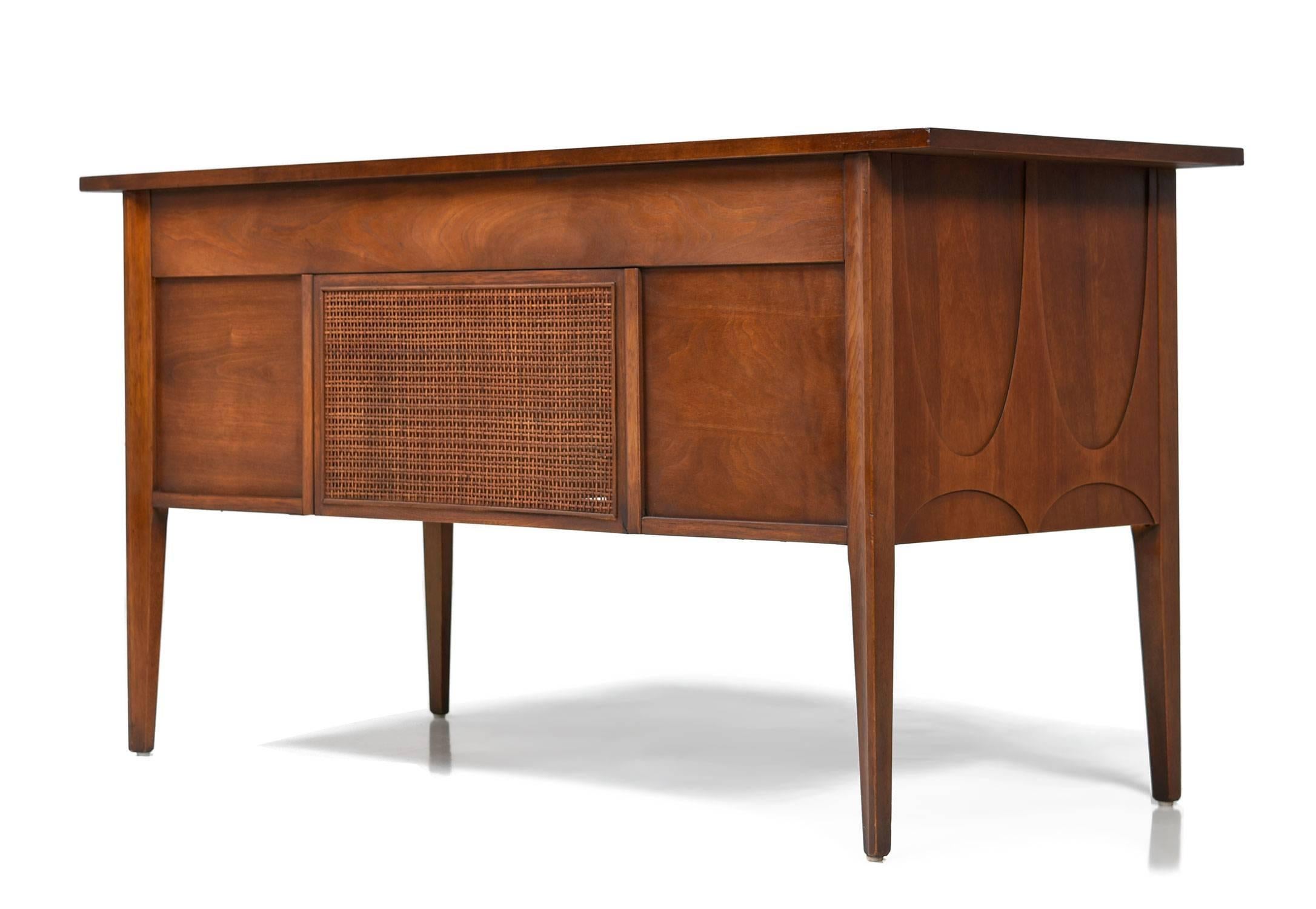 Mid-Century Modern Broyhill Brasilia desk. One of the most beloved collections from the American Mid-Century canon. Designed by Oscar Niemeyer for Broyhill. Vintage, 1960s. Walnut wood construction with original brass pulls. The desk features