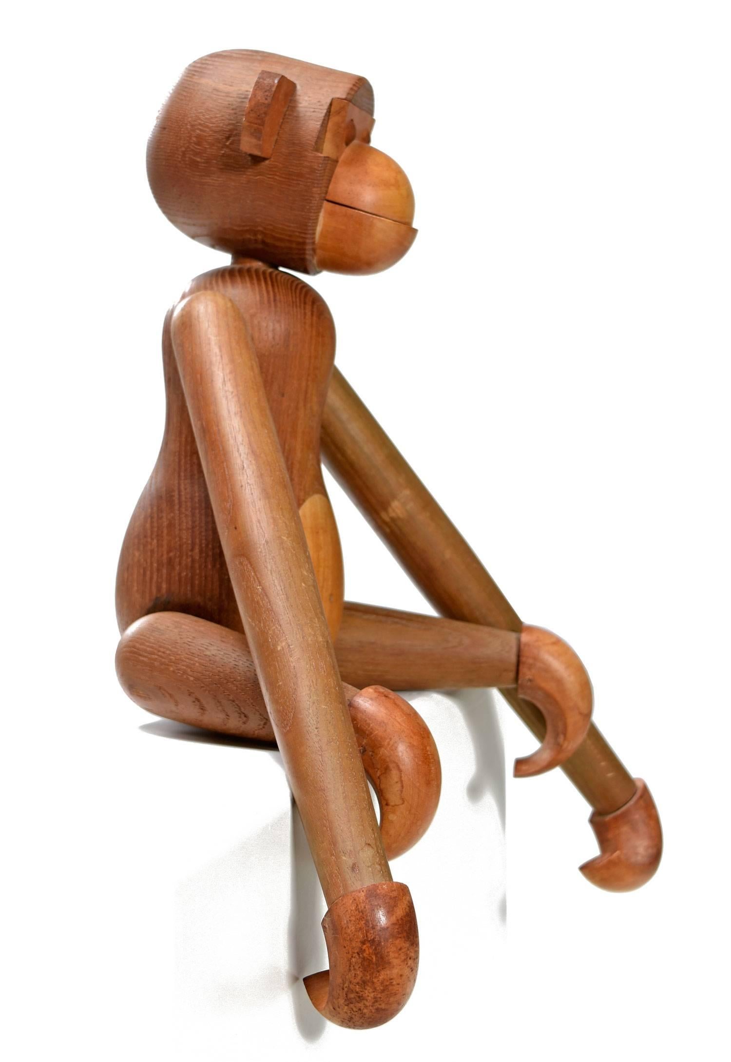 Iconic Scandinavian Modern Kay Bojesen style large wooden monkey, circa 1950s. This playful two-tone carved teak wood toy features movable, rotating arms, legs, and rounded hooked hands and feet. This smart and fun articulating toy can placed
