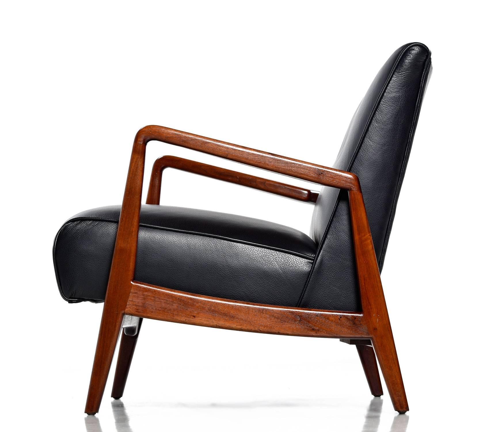 Beautifully restored Mid-Century Modern Jens Risom walnut armchair with new full grain black leather upholstery. The sleek design shows strong influence from Risom's native, Denmark. View from the side, back or front to admire its architectural