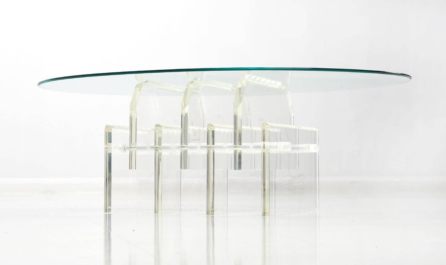 Vintage 1970s coffee table with thick staggered Lucite table base topped with oval glass. The thick slabs of acrylic are artfully arranged in array of varied elevations. Frosted rods run through the panels of Lucite to steady the sculptural form.