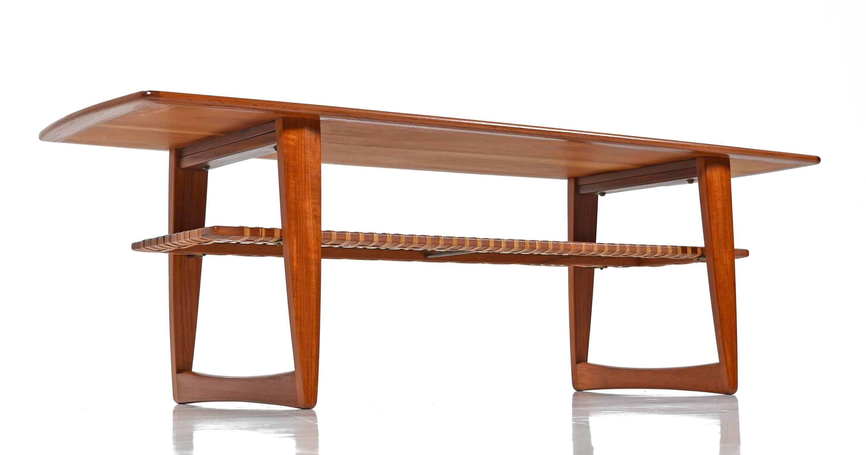 Exquisite vintage 1950s Danish modern coffee table with woven cane shelf beneath the tabletop. This is a remarkable coffee table with a long boat edge tabletop and floating woven shelf. Unusually tall and long, if you need this size, do not pass