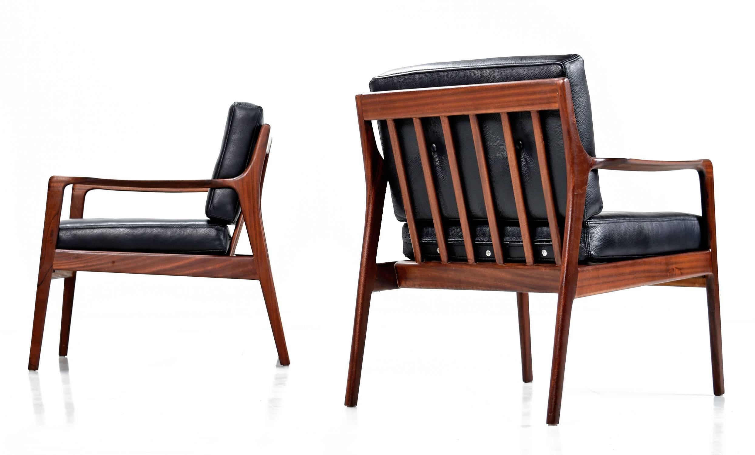 Pair of Danish Mid-Century Modern armchairs restored with new full grain leather upholstery. The early chairs, vintage 1950s, are made of mahogany rather than teak wood, an rarity for Scandinavian furniture. The chairs feature new webbing supports,