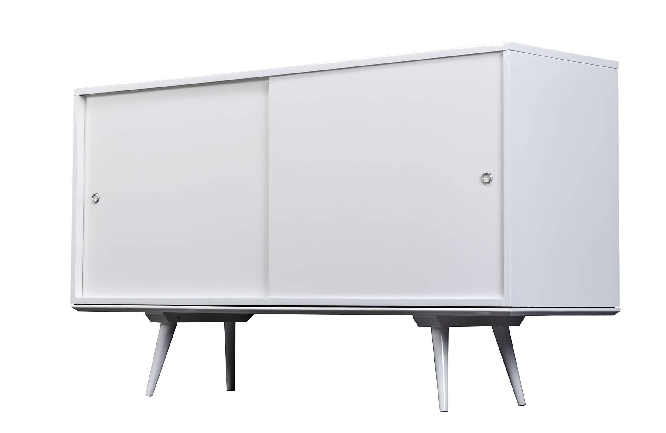 Mid-Century Modern two-piece credenza by Paul McCobb for Planner Group. This unit has been completely, professionally painted in Imron white laquer by an automotive paint shop. The cabinet rests on top of a separate platform base. Features (2) large