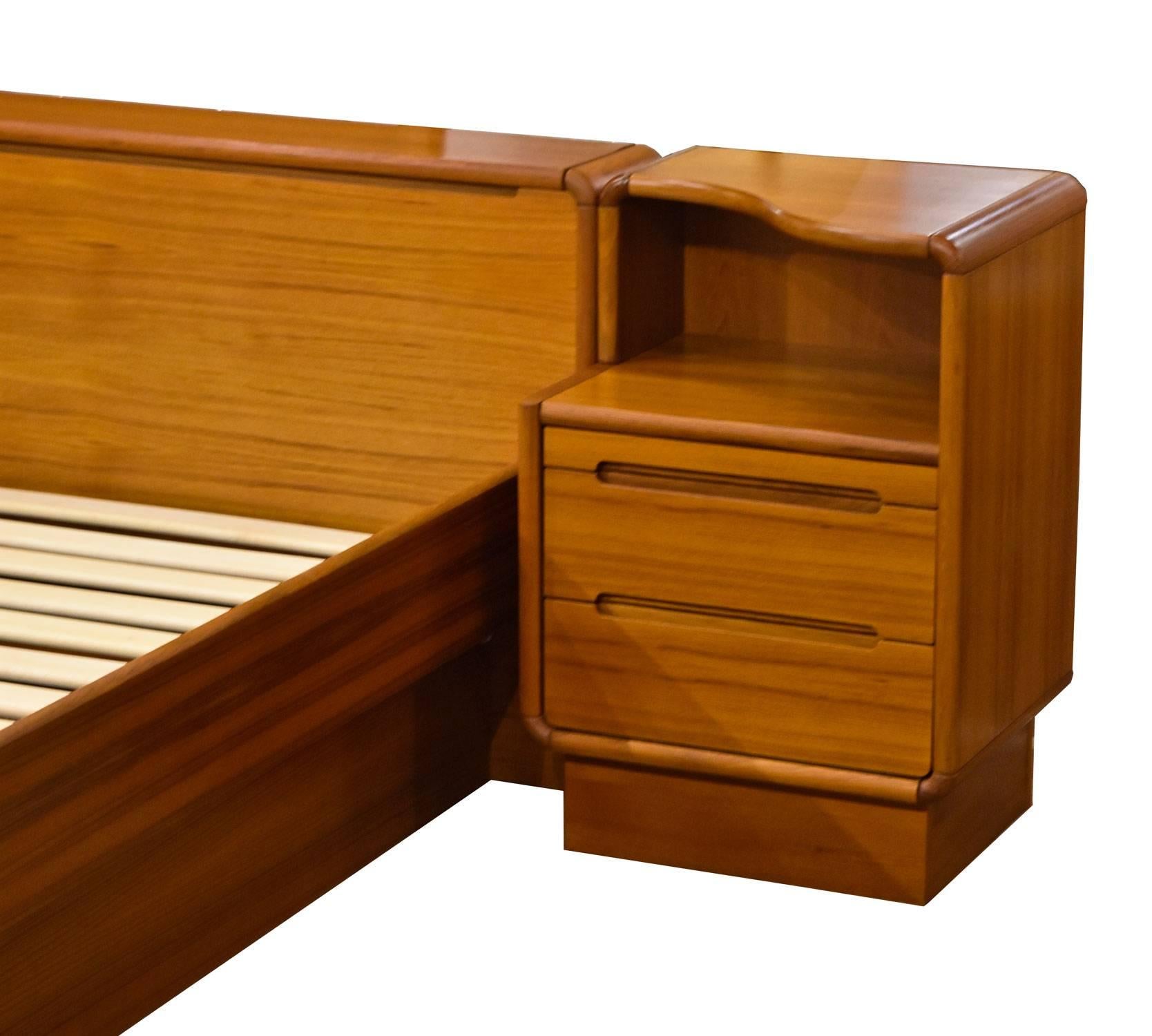 Pre-owned king-size teak platform bed by Sun Cabinet Furniture. The bed comes complete as pictured and includes the two matching nightstands. Danish modern design, made in Thailand. Space saving features include storage compartments in the headboard