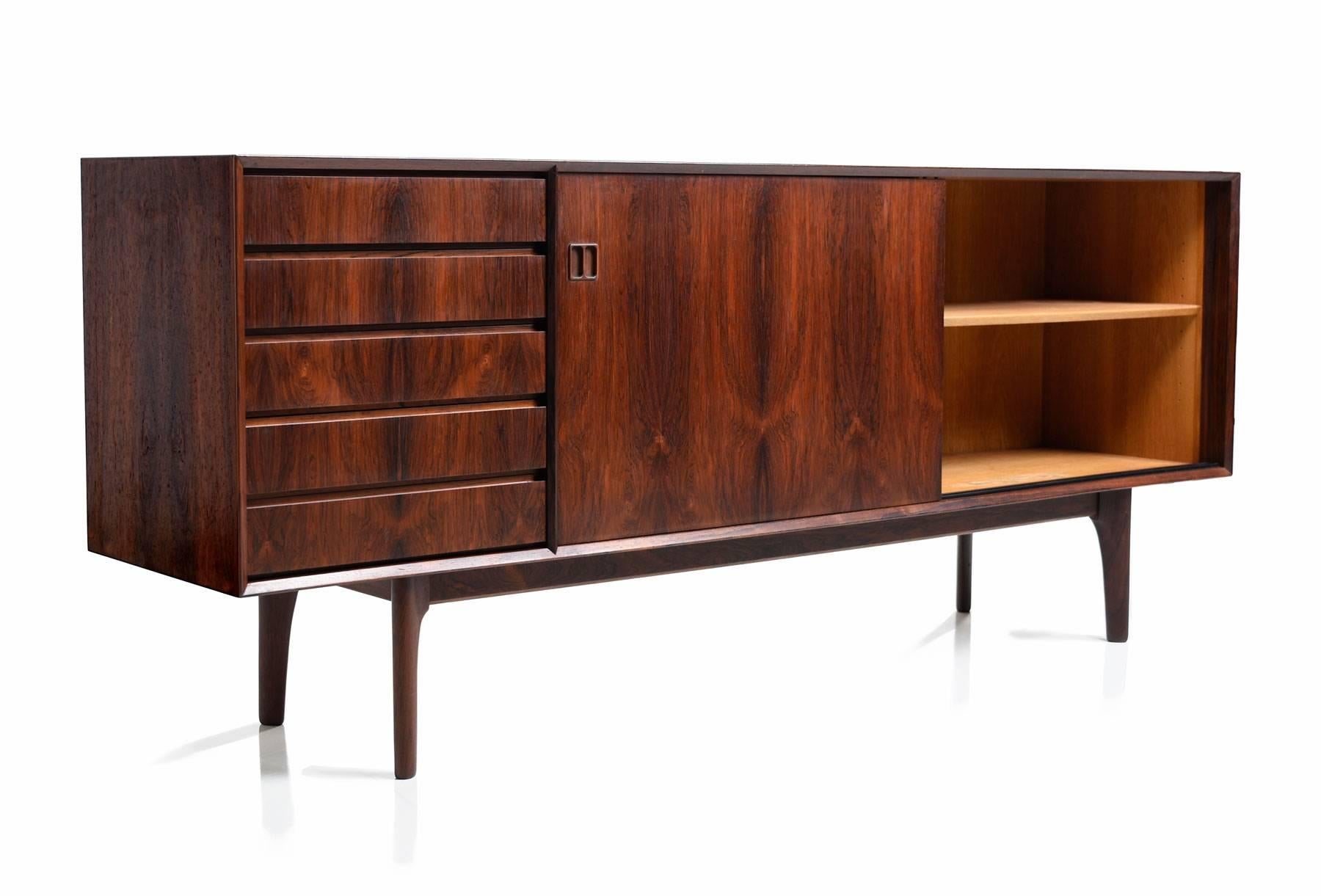 The rich, oxblood colored rosewood is the high water mark of Scandinavian cabinet making. Notice the wild, flaring, cathedral grain. The old growth trees that supplied manufacturers during the midcentury are long gone. Sliding cabinet doors reveal