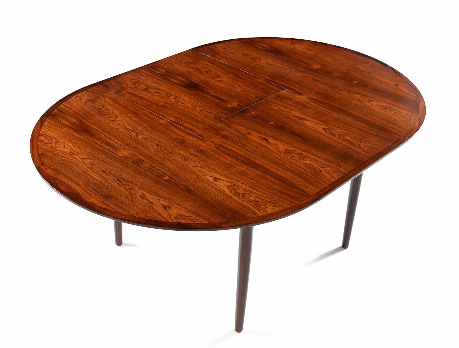 Beautifully restored Danish rosewood dining table with a folding, self-stowing, butterfly leaf at center. Circular when compact, expand the leaf to convert the table to a larger oval. Self-storing leaf is perfect for quick and easy storage when