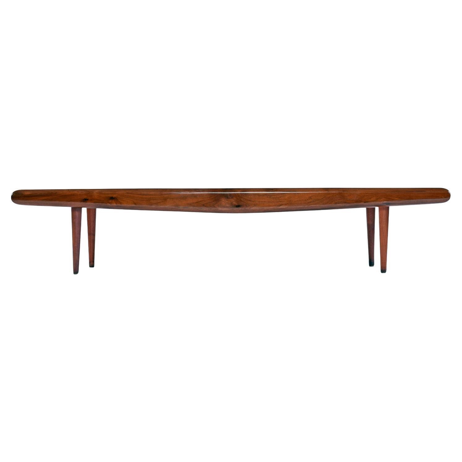 The fiery cathedral grain top of this captivating coffee table is recessed and framed out by solid walnut beams with burl accents. The front and back cross beams of walnut have a slight taper towards the ends to emphasize the look of winged flight.