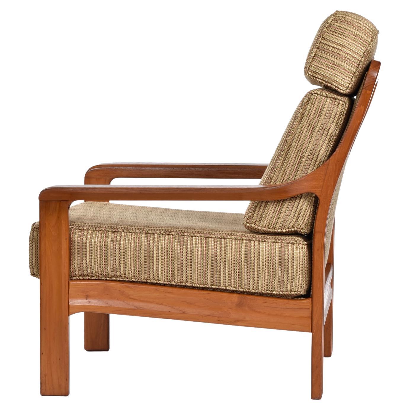 Although not marked by the maker, this exceptional, vintage, solid teak armchair has a distinctive Danish modern design but may actually be Canadian. The chair features an upholstered back framed out with sculpted teak. The blade style arms slope up