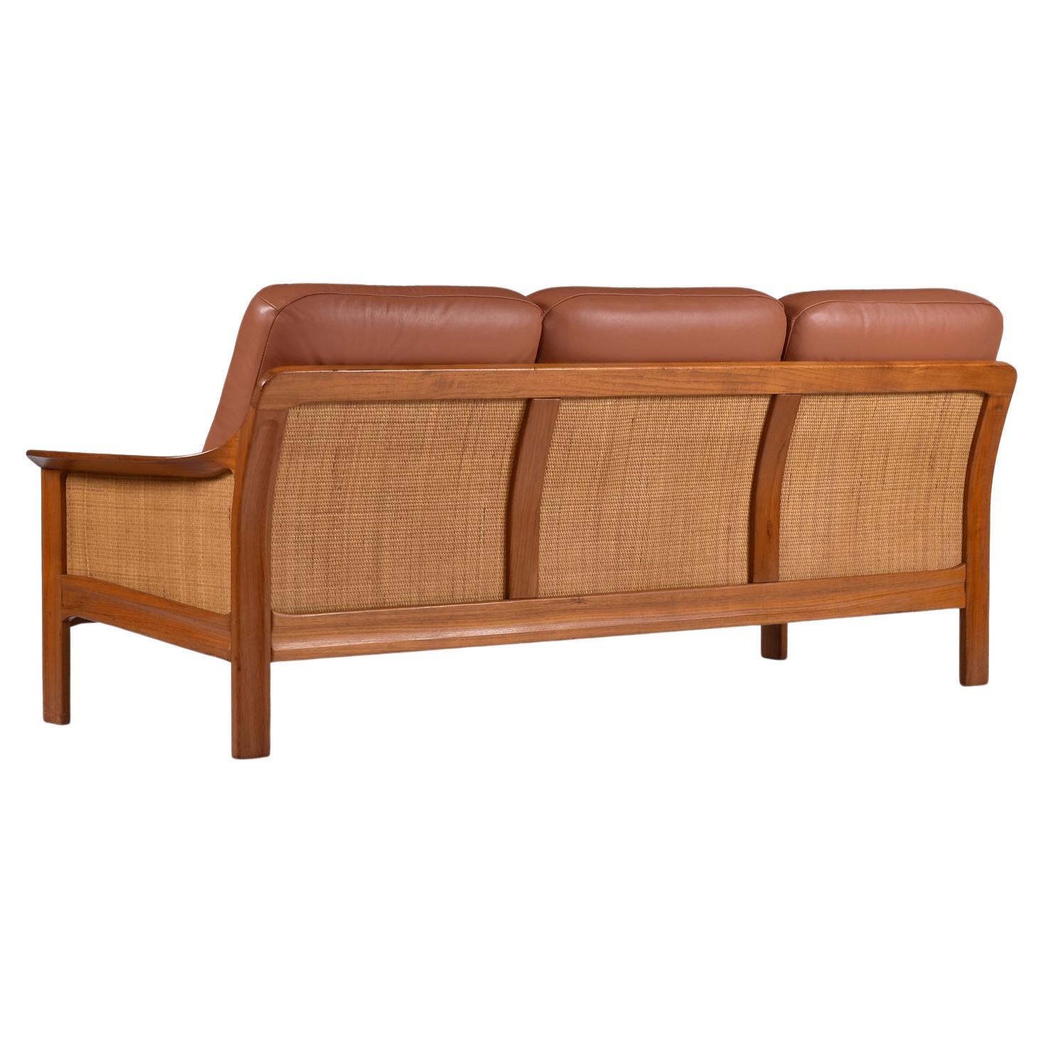Although not marked by the maker, this exceptional, vintage (late 1970s / early 1980s) solid teak sofa has a distinctive Danish modern design but may actually be Canadian. The sofa feature 3-panels of woven reed cane that cover the sides and backs.