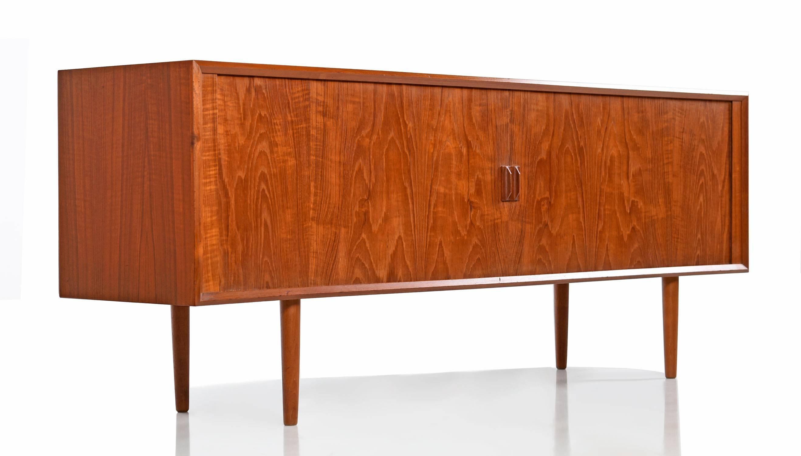 Scandinavian Modern Danish teak credenza by Svend Aage Larsen for Faarup. This simple yet sleek credenza features roll back tambour doors, moveable interior shelves, open cabinets and four drawers with beautiful craftsmanship. The back is finished,