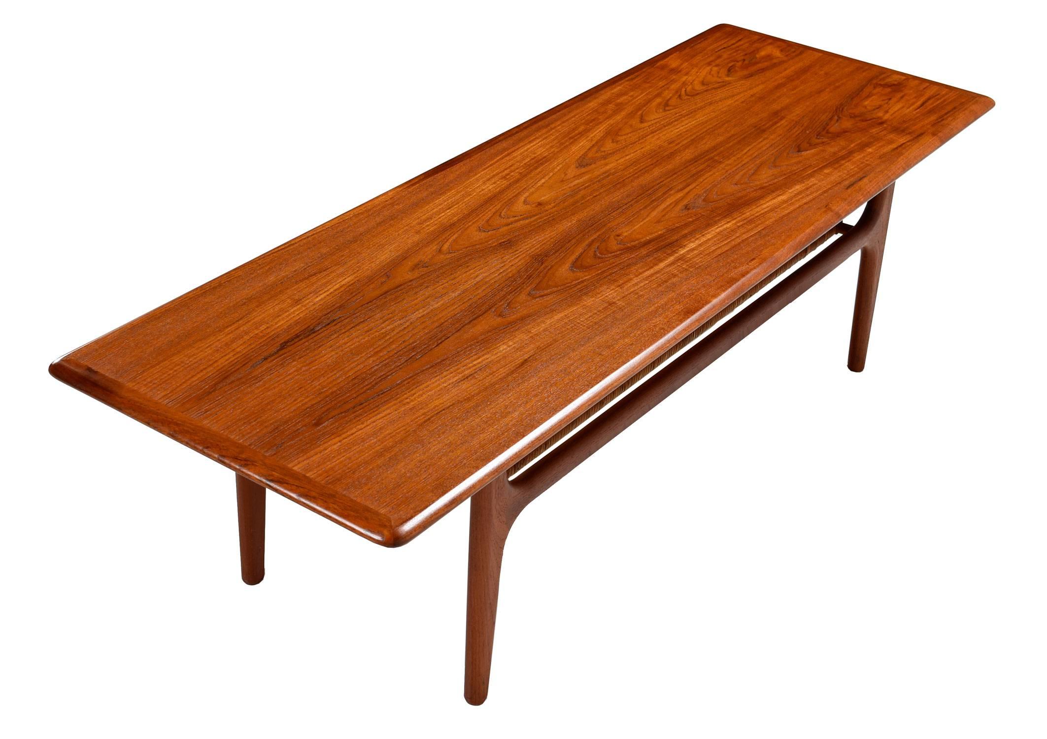 Refinished Mid-Century Modern Danish teak coffee table by Trioh Møbler. Two tier design with caned shelf at bottom. Elegant Scandinavian styling throughout with unparalleled attention to detail and premium teak construction. Matching end table