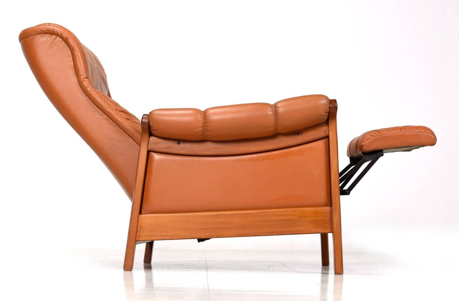 Vintage Danish modern teak recliner with original leather upholstery. Exceptionally comfortable with its well padded seat and arms. Lean back to push the chair into a reclining position and elevate the footrest to varying degrees. This is a time