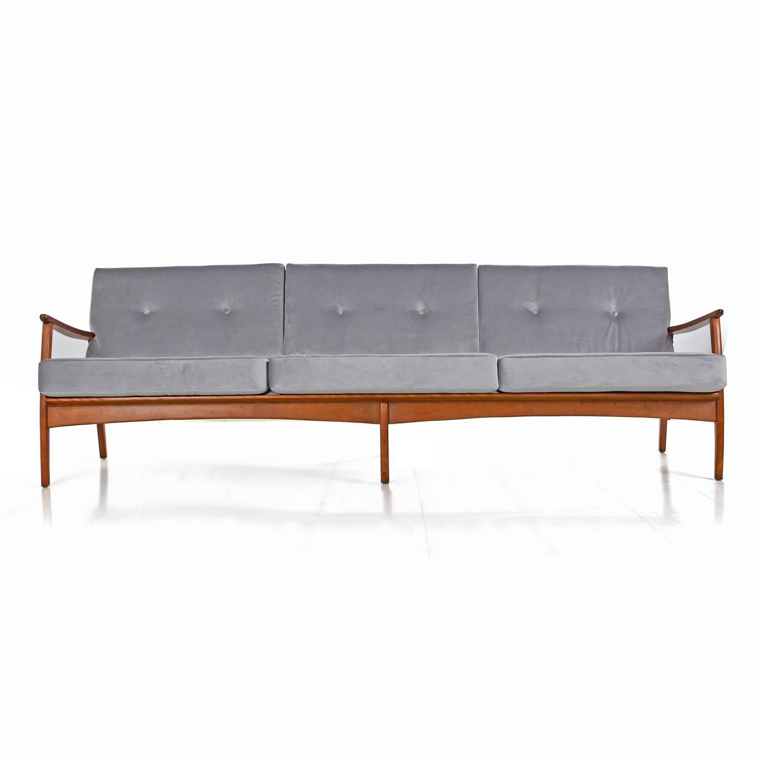 Retro Eames era sofa with Danish modern styling. Note the remarkable subtle detailing in the wood frame. Angled back legs add visual dynamism. This angle gives a gentle reclined position to the couch, enhancing comfort. The wide, sculpted arms taper