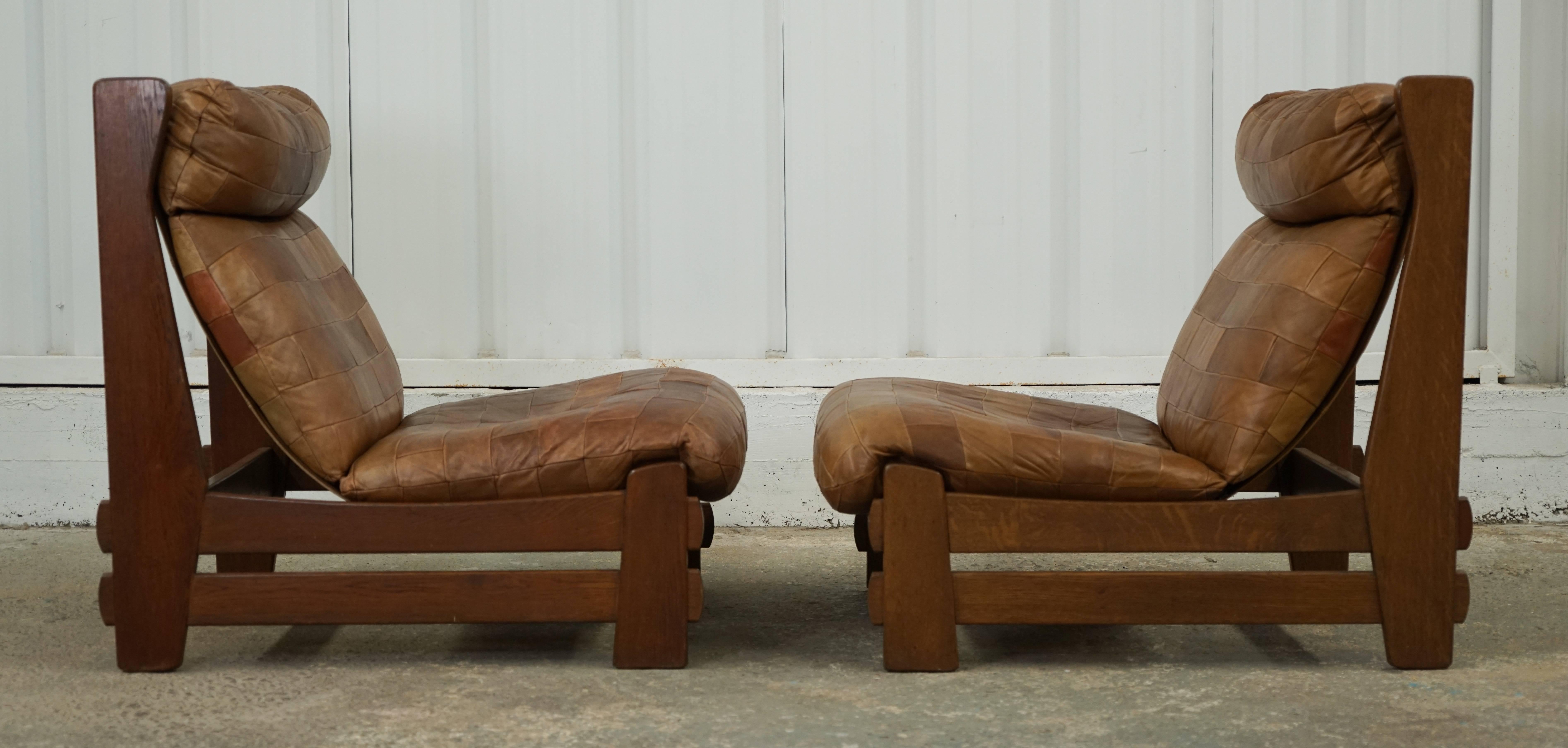 A pair of 1970s oak-framed slipper chairs by De Sede in Switzerland with perfectly aged patchwork leather cushion upholstery.