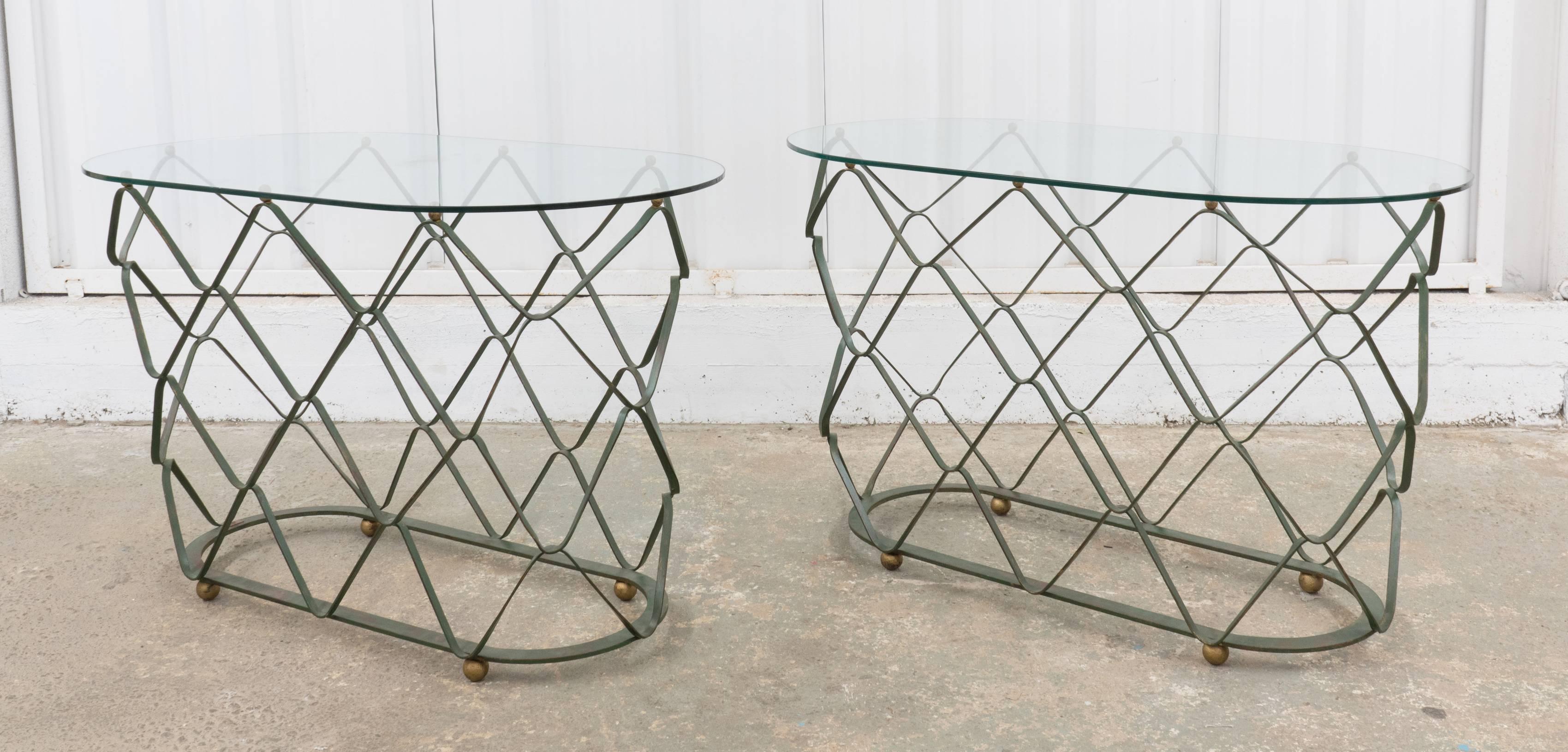 Two consoles with a 'woven' iron base, oval glass tops, and gold ball feet created in France in the early 1950s in the style of Jean Royere. Iron is a dark, neutral green shade.