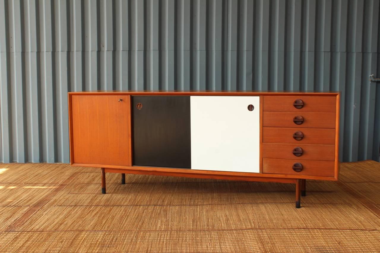 Impressive Danish modern teak credenza offering ample amounts of storage. Features sliding center drawers, a locking cabinet door with original key and five drawers with sculpted afromosia pulls. Centre doors are also reversible giving you the