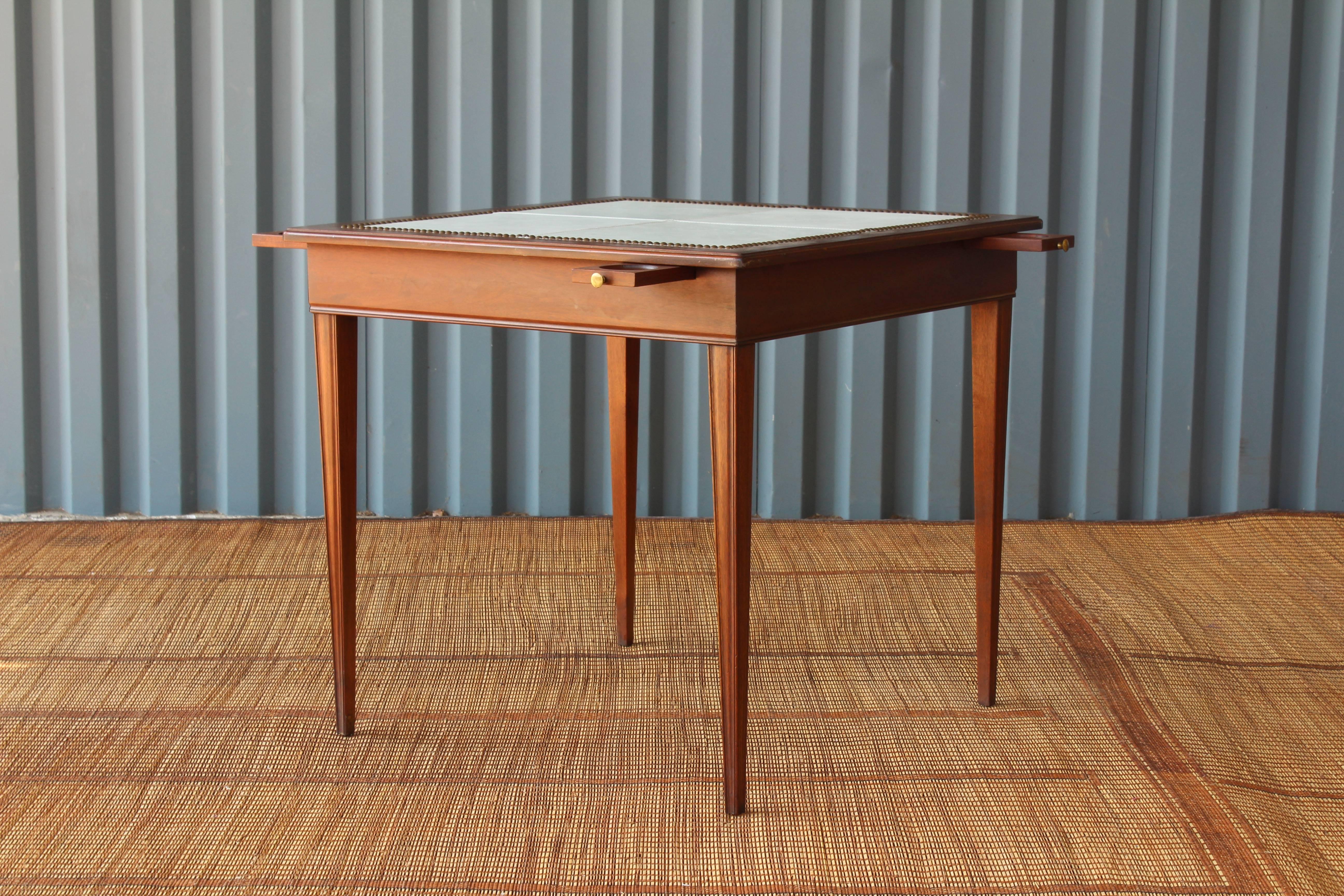 Vintage game table and matching chairs. The game table features a lovely new leather top in light blue with brass nailhead detailing along the edges. The table also features four pull-out cup holders. The matching set of four chairs have been