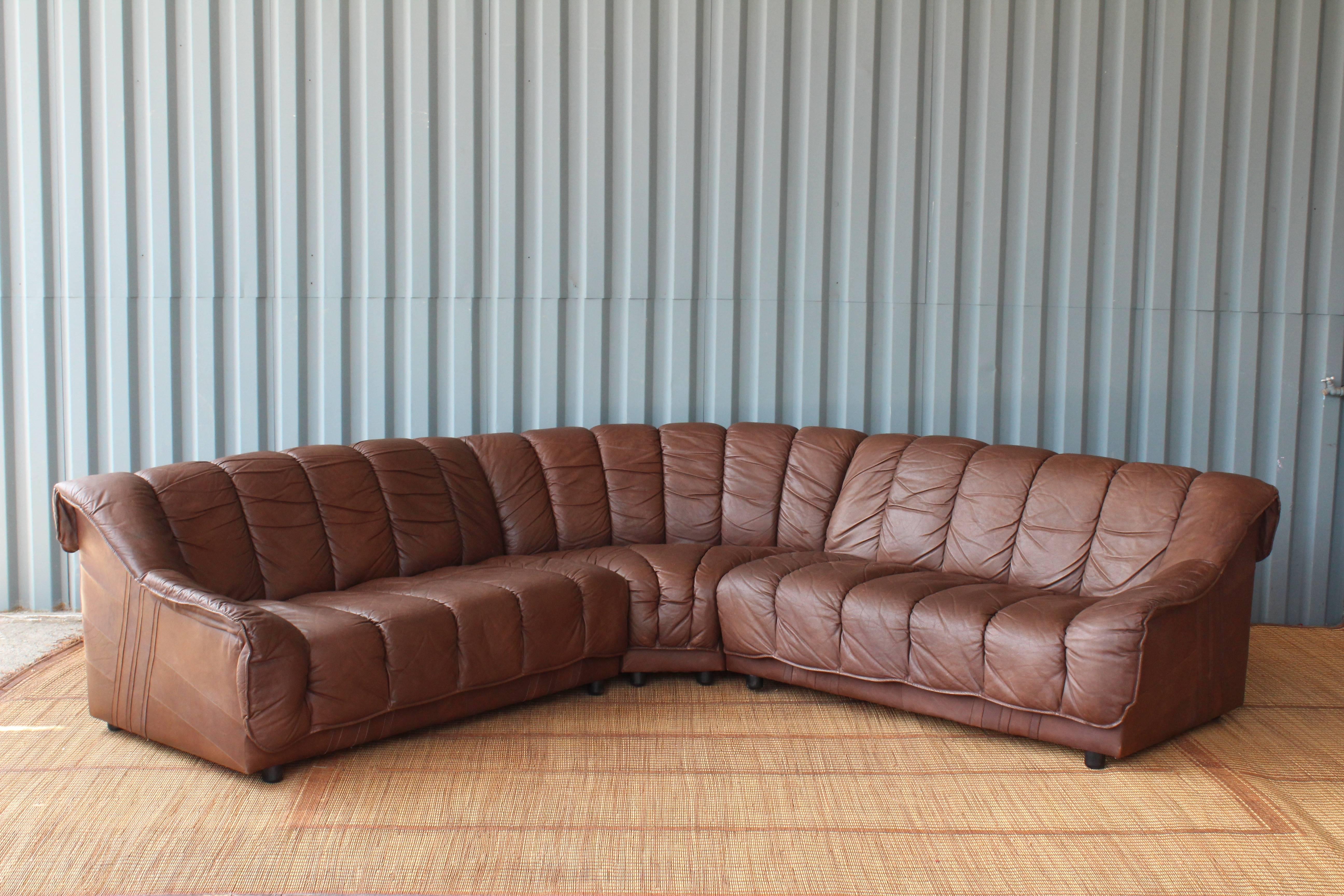 Impressive, 1970s sectional sofa and matching chair in leather. Exceptional condition and extremely comfortable. This sofa connects in three separate pieces with hardware for easy attachment. The leather has been recently cleaned and conditioned.