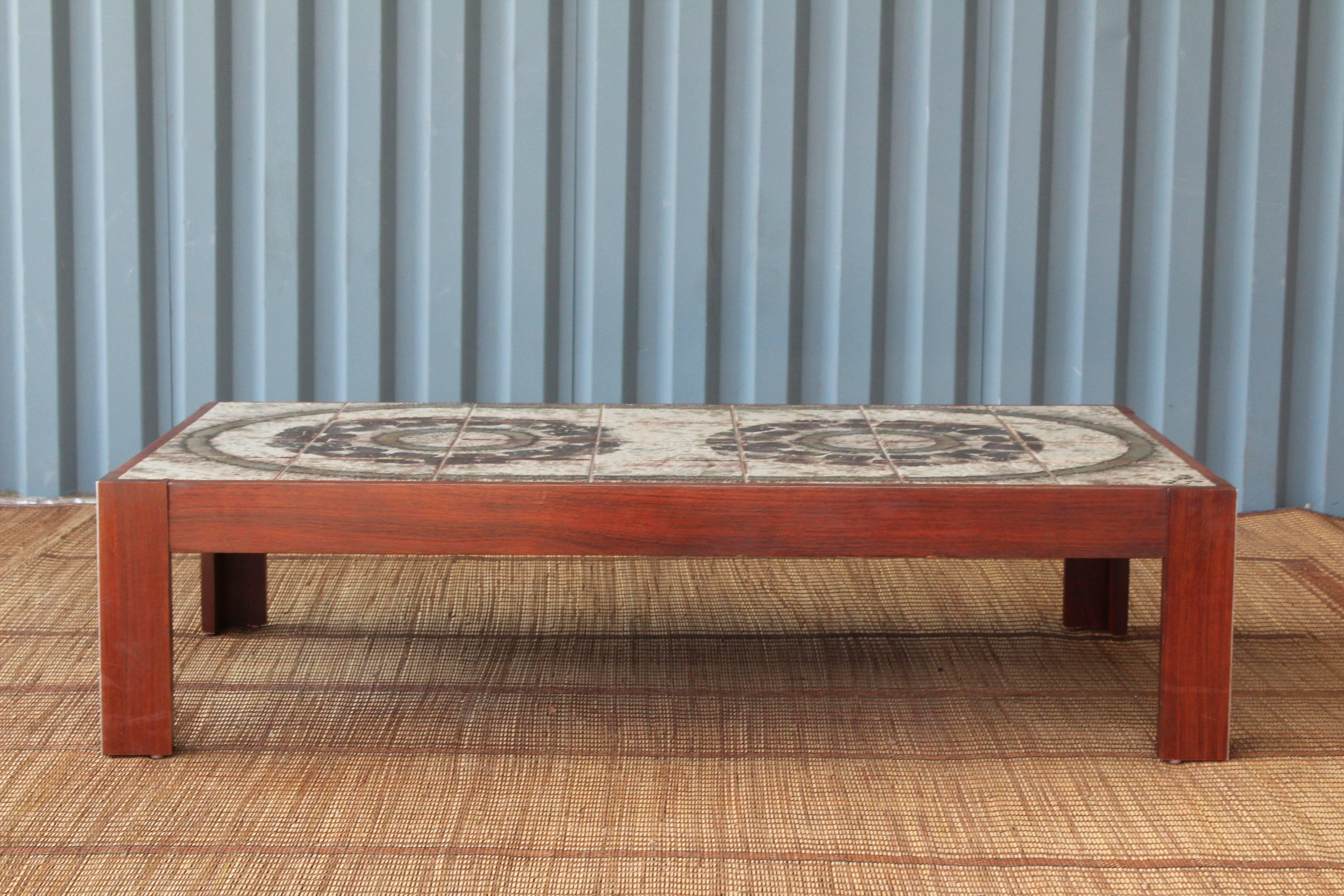 Danish modern coffee table with a beautifully designed glazed tile top. The edges of the legs feature an interesting inlaid metal detailing. Signed 'Ox Art 78'.