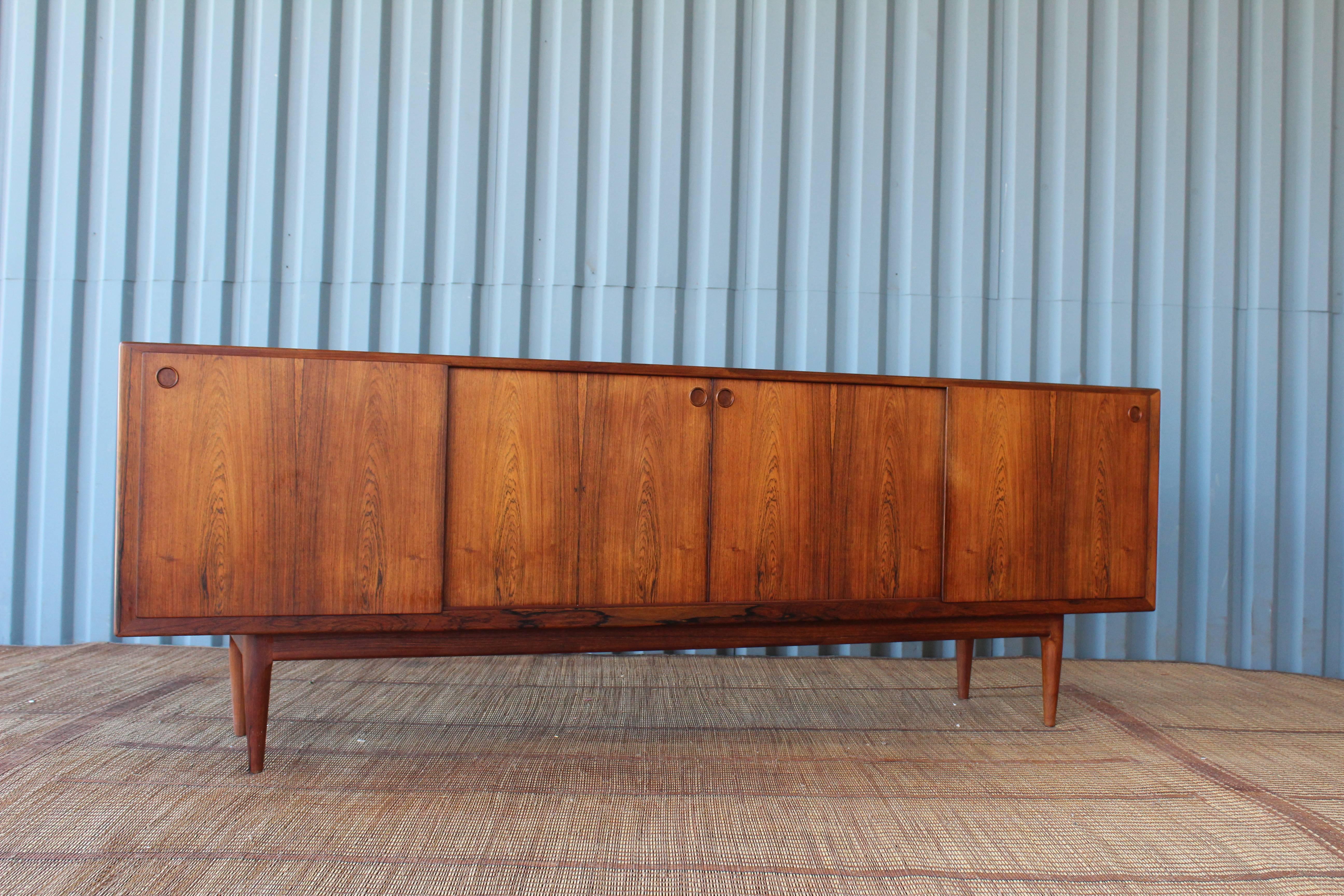 Substantial Danish credenza in beautiful Brazilian rosewood. Features four sliding doors and a gorgeous soaped oak interior. Behind the doors reveal plenty of storage with dovetail felt lined drawers and adjustable shelving. A truly remarkable piece