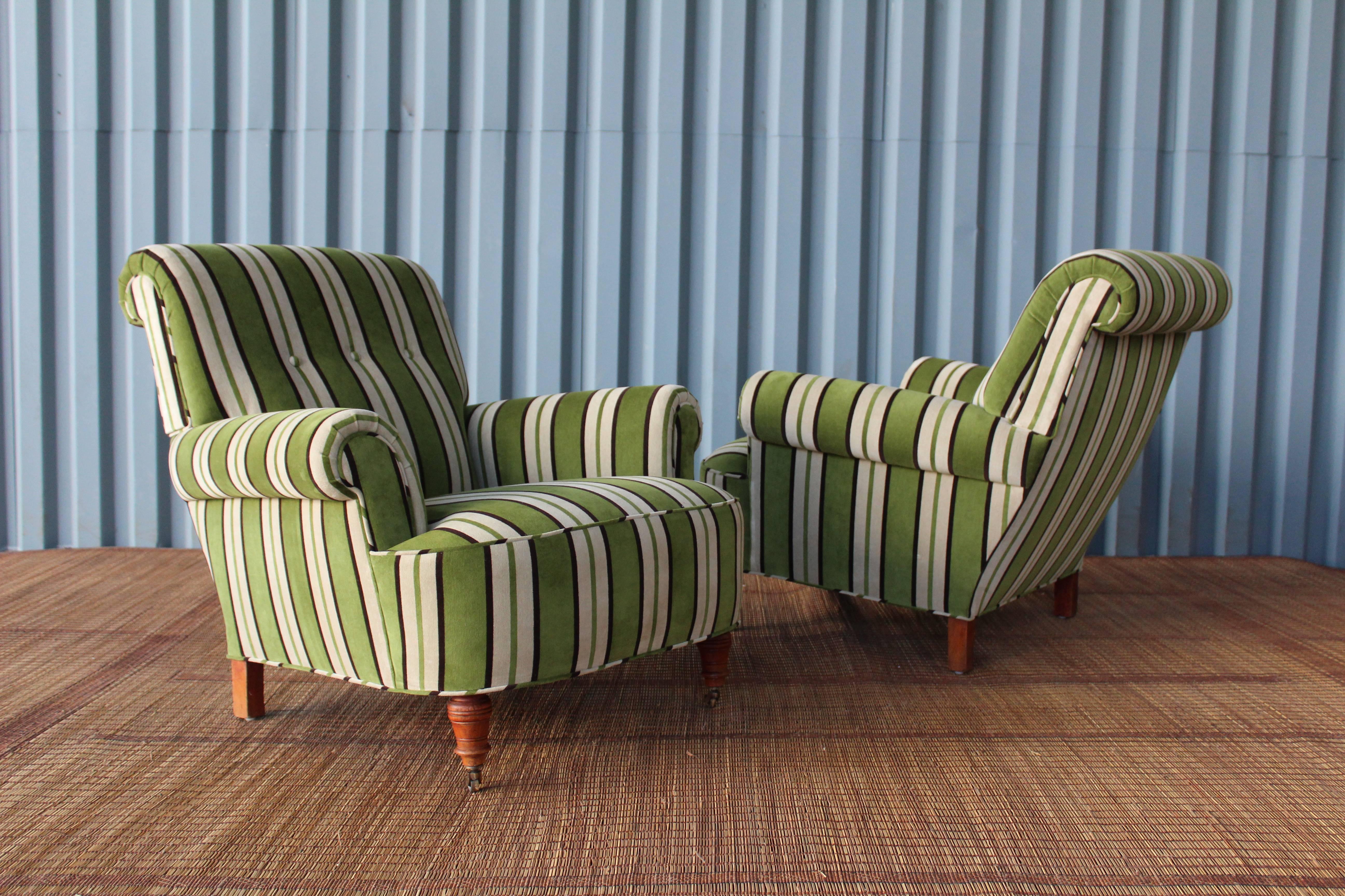 Pair of 1940s traditional armchairs. Recently upholstered in a luxurious green velvet striped fabric. Refurnished with new rolling casters on the front of each chair.