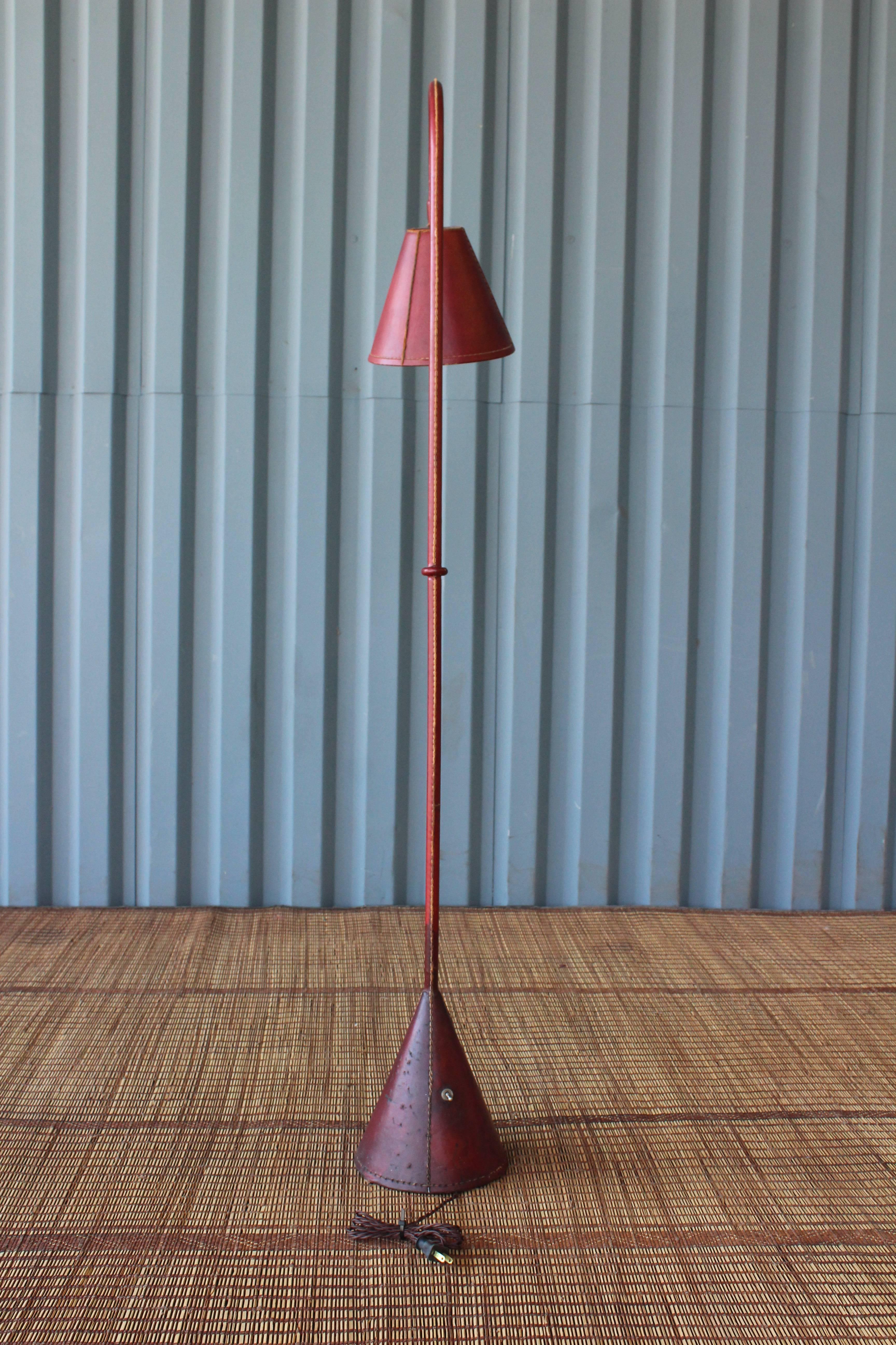 A red leather-wrapped floor lamp by Jacques Adnet, France, 1950s. Leather shows an aged minor age appropriate wear and patina. Newly rewired for U.S standards.