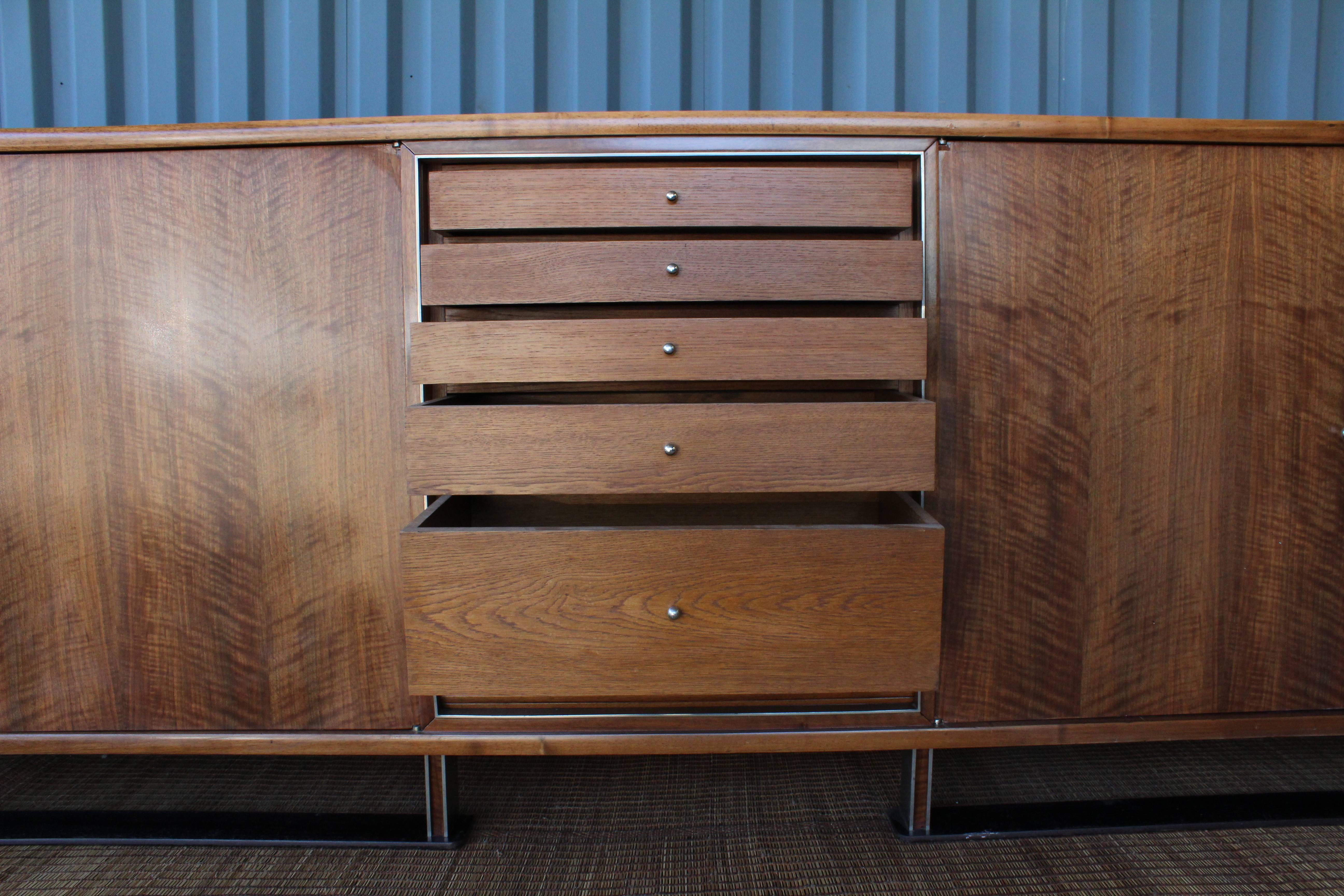 A substantial Paul Dupré-Lafon cabinet constructed in walnut, nickel and iron. Features a drop-down tambour door concealing a suede lined fitted interior with five center drawers. In excellent condition and expertly refinished. Originating from