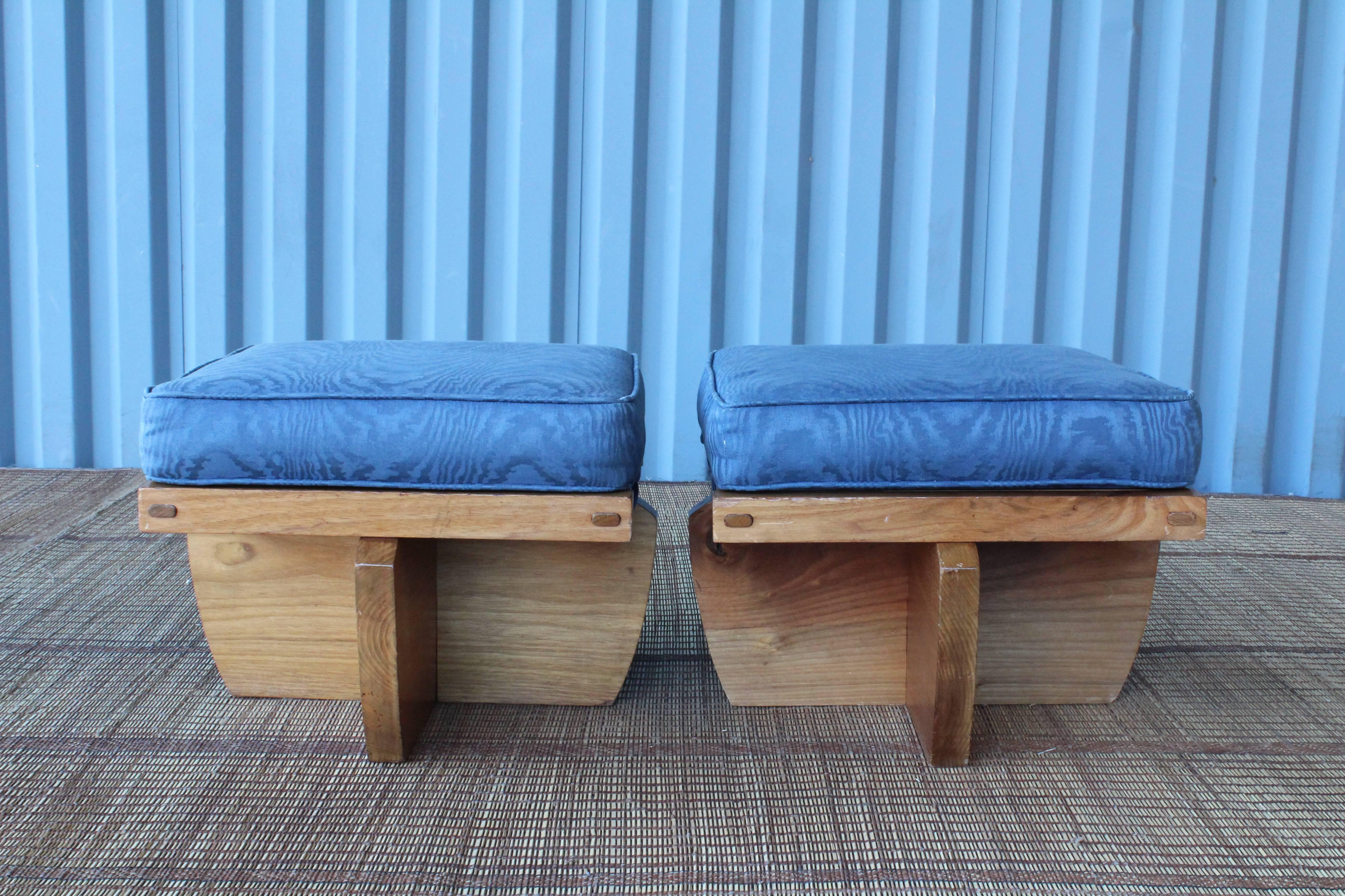 Pair of solid walnut stools in the manner of George Nakashima. These stools can be used with or without the snap on cushions and feature beautiful walnut tops. Cushions are upholstered in a blue moire fabric.