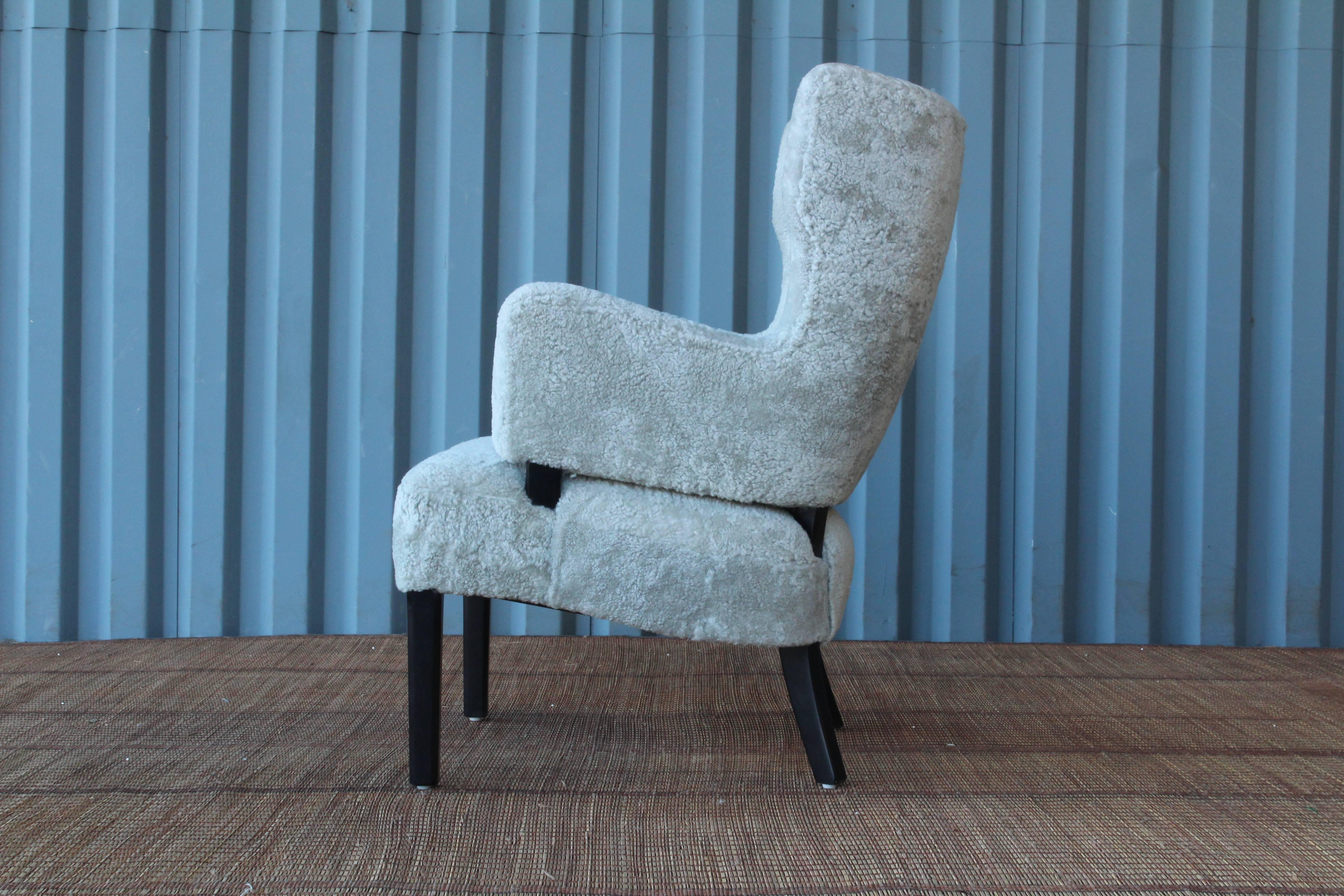 Beautiful 1940s Danish armchair upholstered in a light grey sheepskin and black lacquered legs.