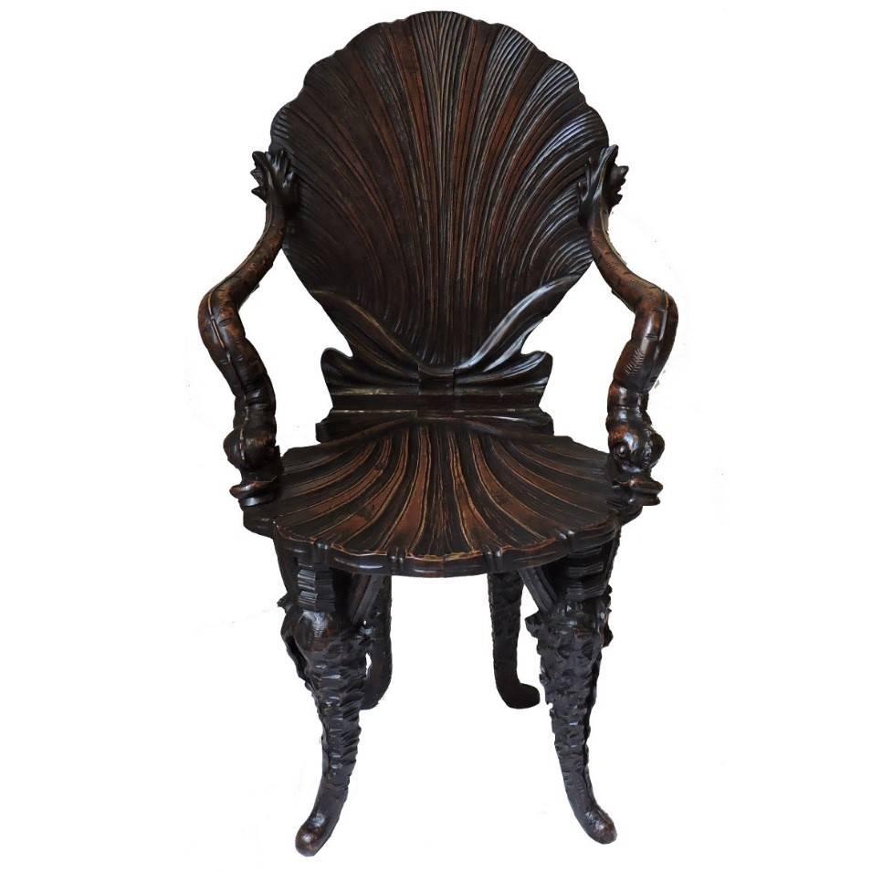 This unique Italian grotto chair has a large-scale shell motif on the back and seat. Carved sea creature motif adorns the arms and legs. Kept in pristine condition with (rare) finished and craved back in stained wood finish.